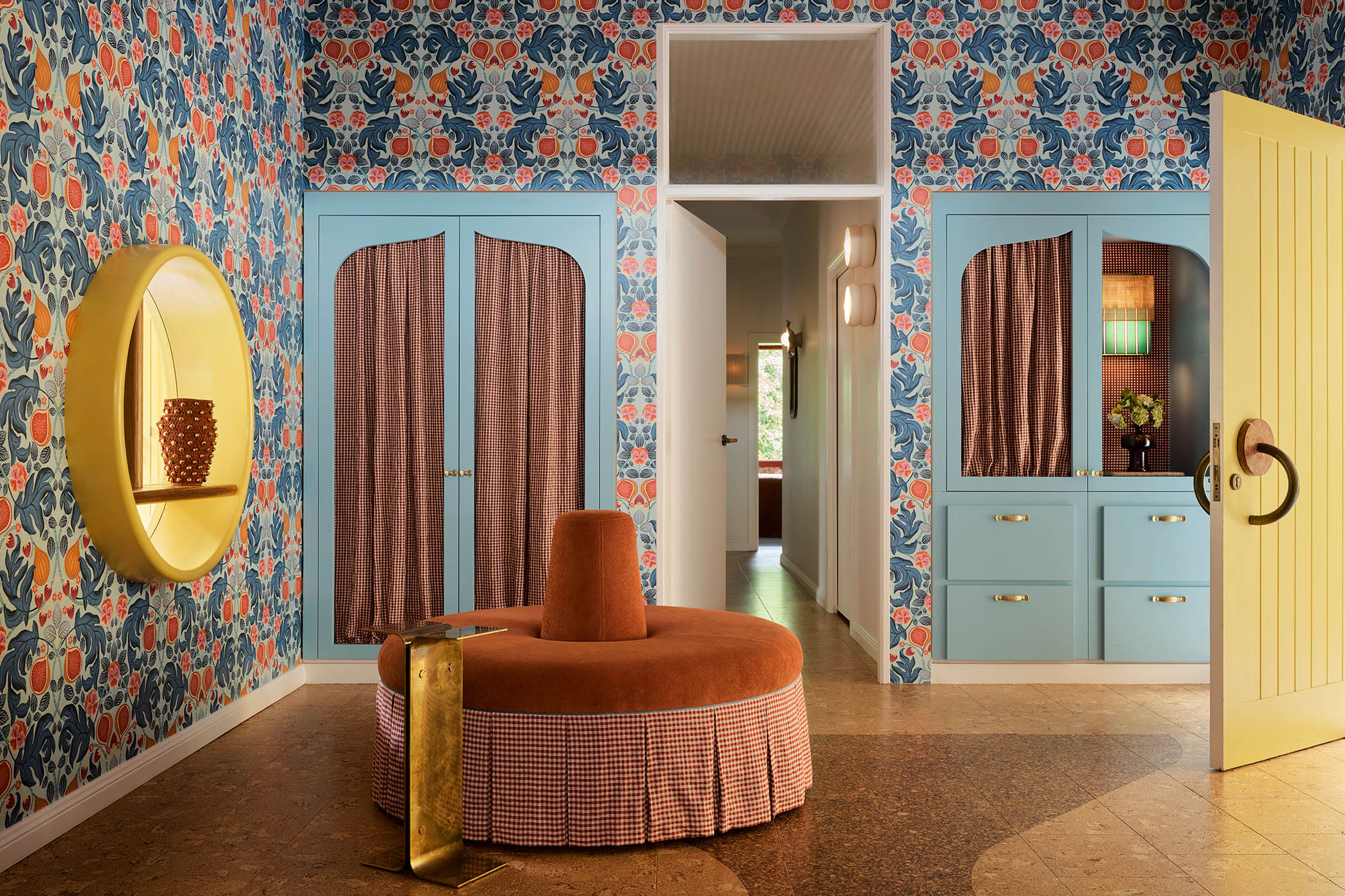 True blue: a circular ottoman and cabinets by YSG in the hall behind a yellow front door