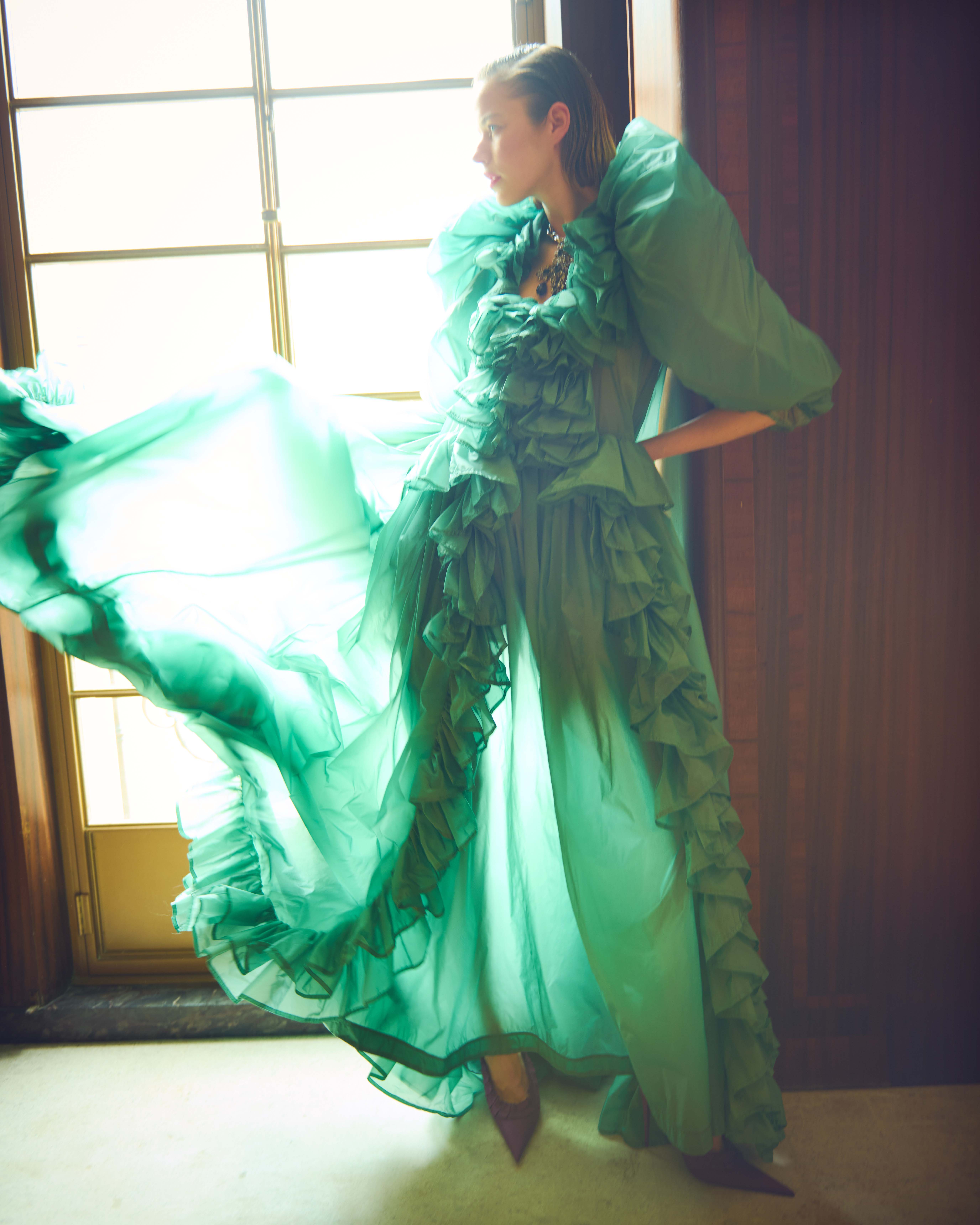Alex wears green long dress with ruffles, necklace and slingback pumps by Saint Laurent by Anthony Vaccarello
