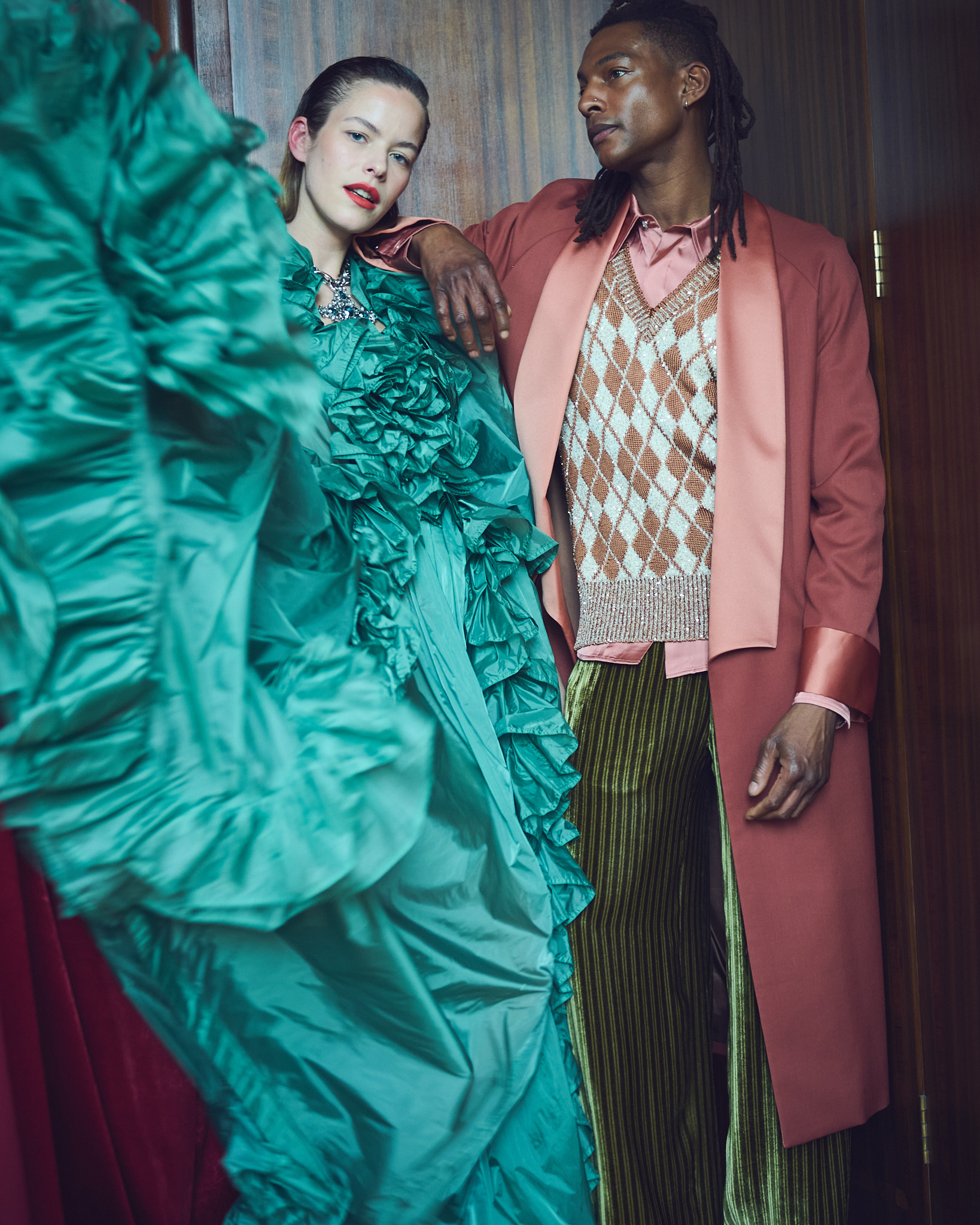 Alex wears ruffle dress and necklace by Saint Laurent by Anthony Vaccarello; Ty wears coat, shirt, jumper, trousers and shoes all by Amiri