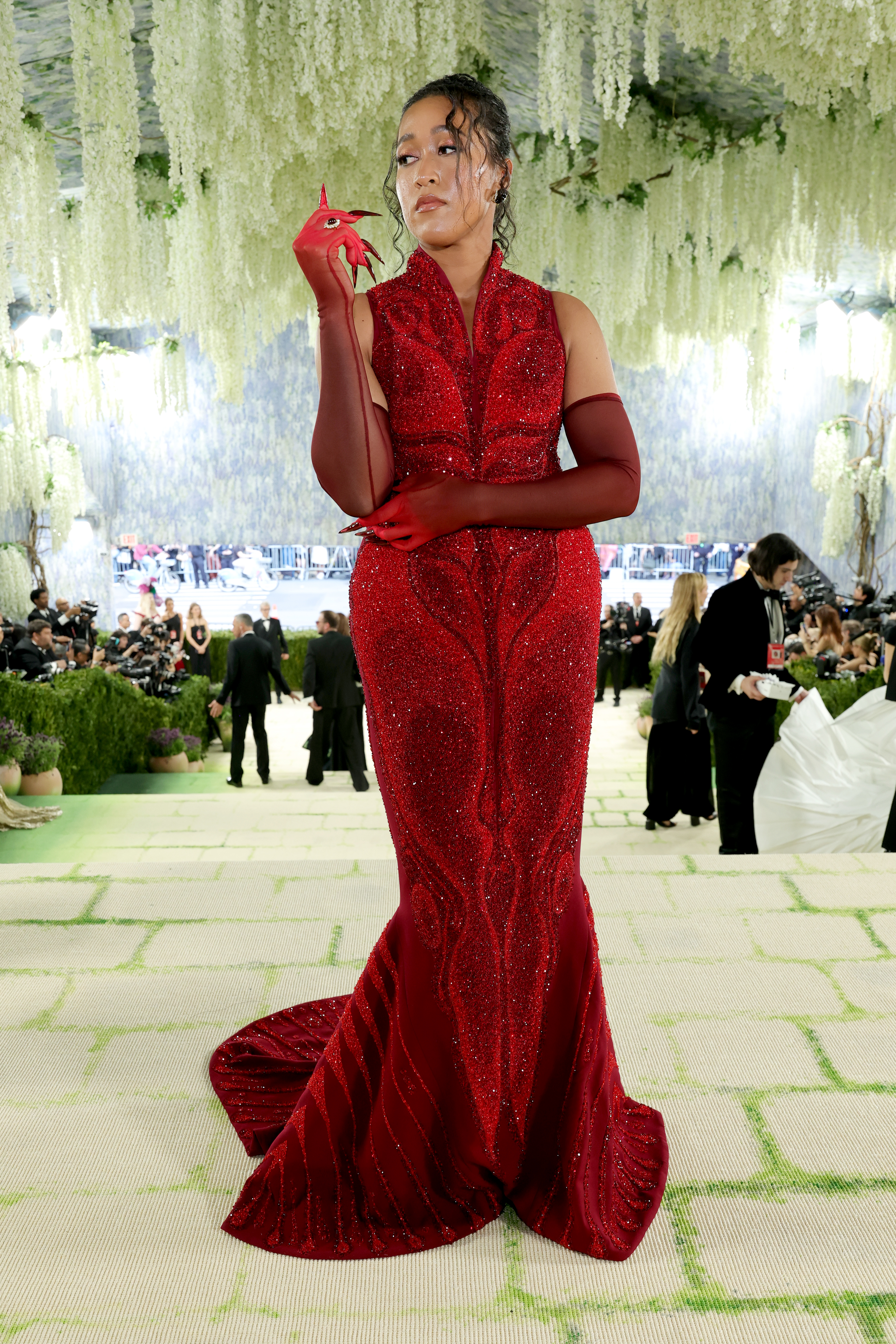 Naomi Osaka’s the ”The Red Within” by Robert Wun was a two-part act on the red carpet. Osaka wore a sculpted ivory coat, with open seams that exposed red Swarovski crystals. Removed, it revealed a deep-red crystal gown consisting of 659,000 stitches of intricate embroidery and thousands of faceted Swarovski crystals in four shades of red, crafted through 3,280 hours of handwork.