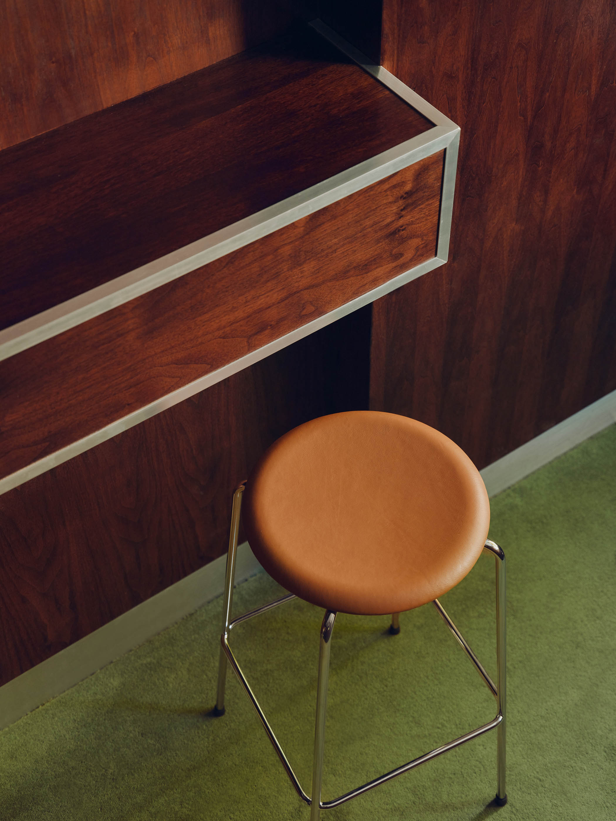Enjoy coffee and a bar while sitting on an Arne Jacobsen stool upholstered in honey-coloured leather