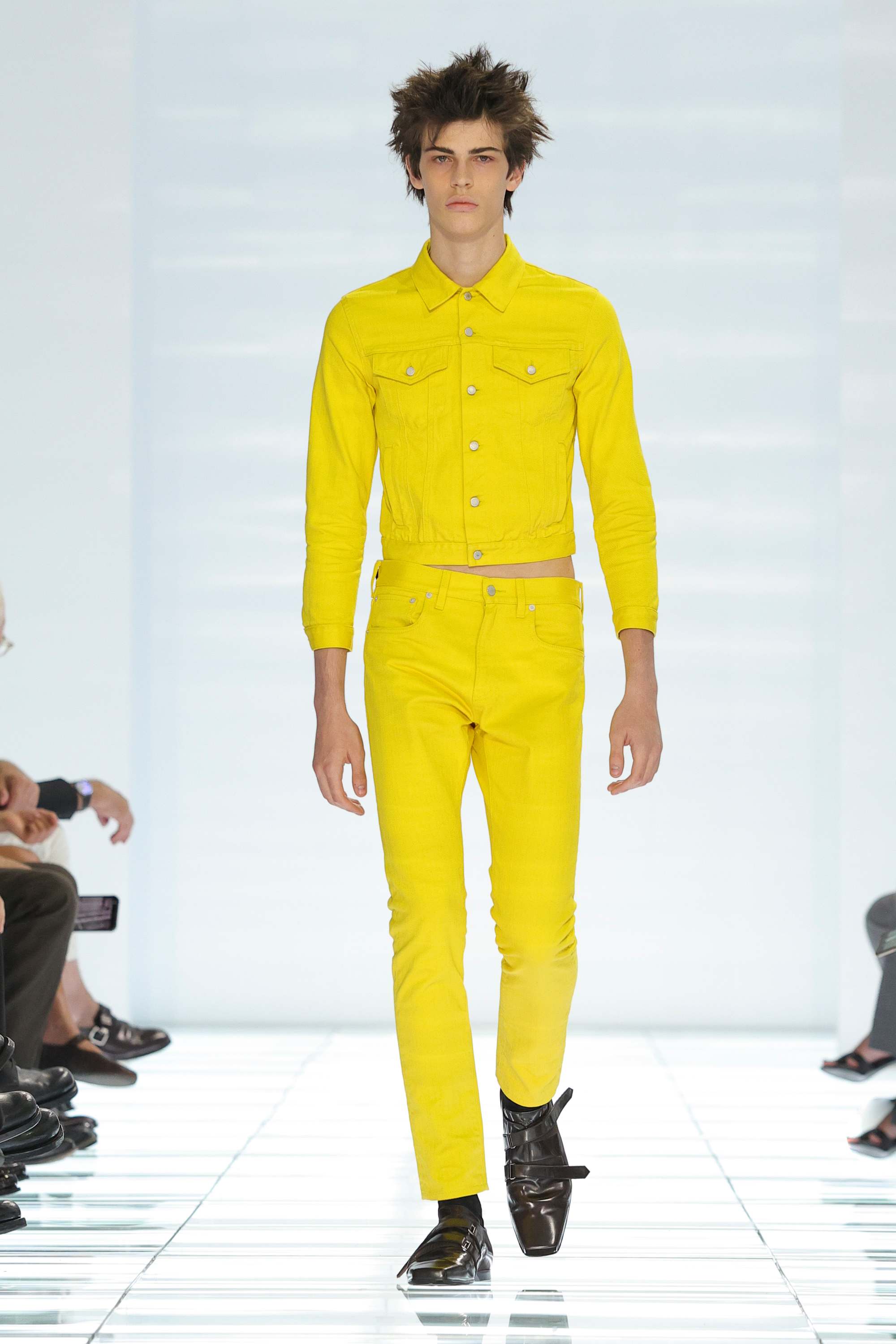 PRADAAssume the brace position: skinny jeans are back, but not as we know them. Prada sent the skinniest of classic five-pocket jeans down the runway in shades of banana yellow, white and hot pink – while blue denim was notable by its absence . The slightly cropped jeans were shown with matching shrunken denim jackets. The same silhouette came in leather, grey check wool and a semi-sheer organza-type fabric that gave an x-ray effect to the seam details. The youthquake denim seemed to come out of co-creative director Raf Simons’ wheelhouse while Mrs Prada’s hand was clear in the vintage prints and colour palette. In a break from tradition the usual backstage post-show interview was cancelled; instead, quotes and notes were circulated to press. “Everything looks simple, but it is not.” Simons said of the collection titled Clarity . “It is about being extremely decisive, and precise,” he added. Accessories were streamlined – pouch bags clipped to belt loops, earrings that look like rings, scarves wrapped around midriffs, bridging the gap between waistband and shrunken top. Looks were finished with triple-strap velcro shoes with a squared-off toe. Everything felt considered and linear, without fuss. “There is nothing that I hate more in this period than useless design,” said Prada.
