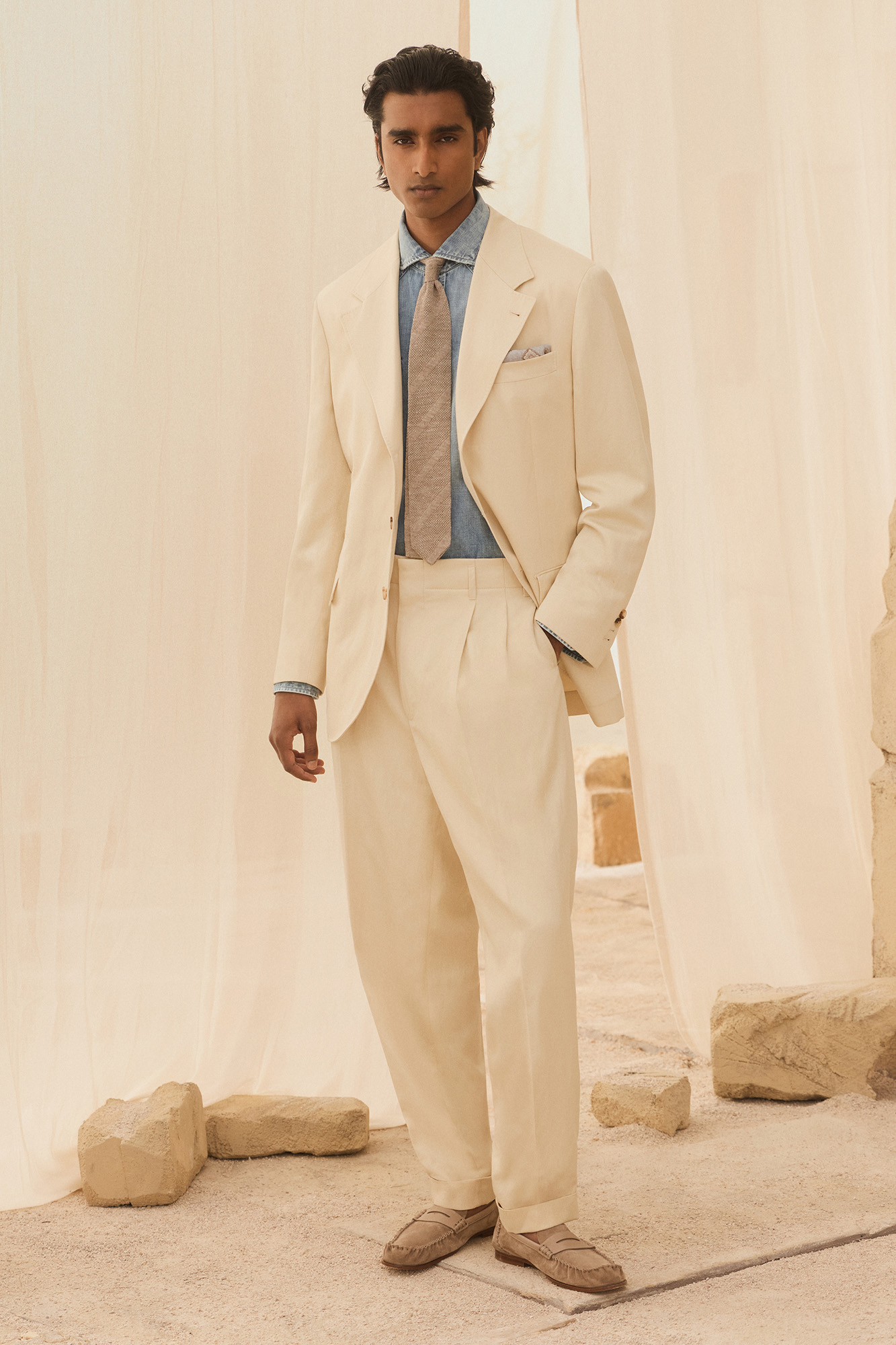 BRUNELLO CUCINELLIBrunello Cucinelli mulled over Shakespeare’s “Thought is free” quote from The Tempest as he worked on SS27. Designed with free thinkers in mind, the collection is dedicated to the contemporary man with a strong sense of identity. “It is a state of mind. An aesthetic attitude shaped by individuality,” declared the show notes. New for SS27 is a resin-dyed cable knit that results in a sun-bleached effect in shades of raspberry, apricot, peach blossom, and aqua green. Cucinelli’s brand of discreet and refined luxury was evident in the fabric choices – washed cottons and linens, supple suedes and ultra-lightweight wools. There was a balance between structure and ease, think  tailored blazers paired with worn-in denim and evening jackets worn with pleated trousers and jumpers tied over the shoulders.