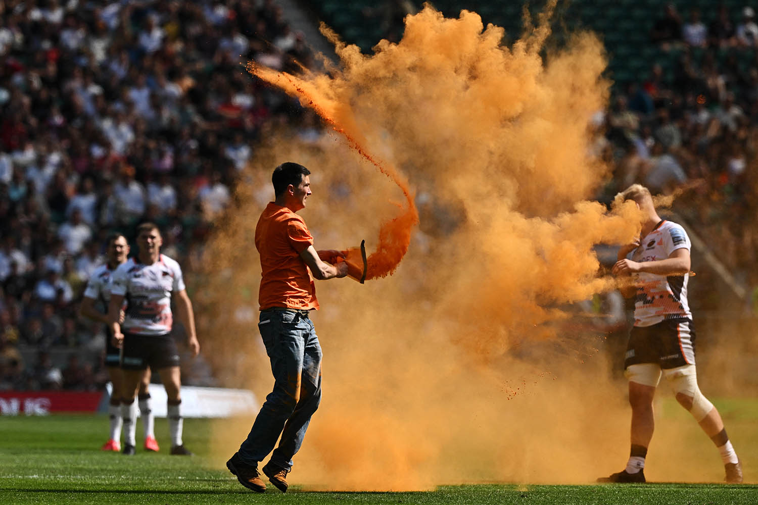 An activist spreads orange powder as a sign of protest during the Premiership Final rugby union match. Photograph: Ben Stansall/AFP via Getty Images