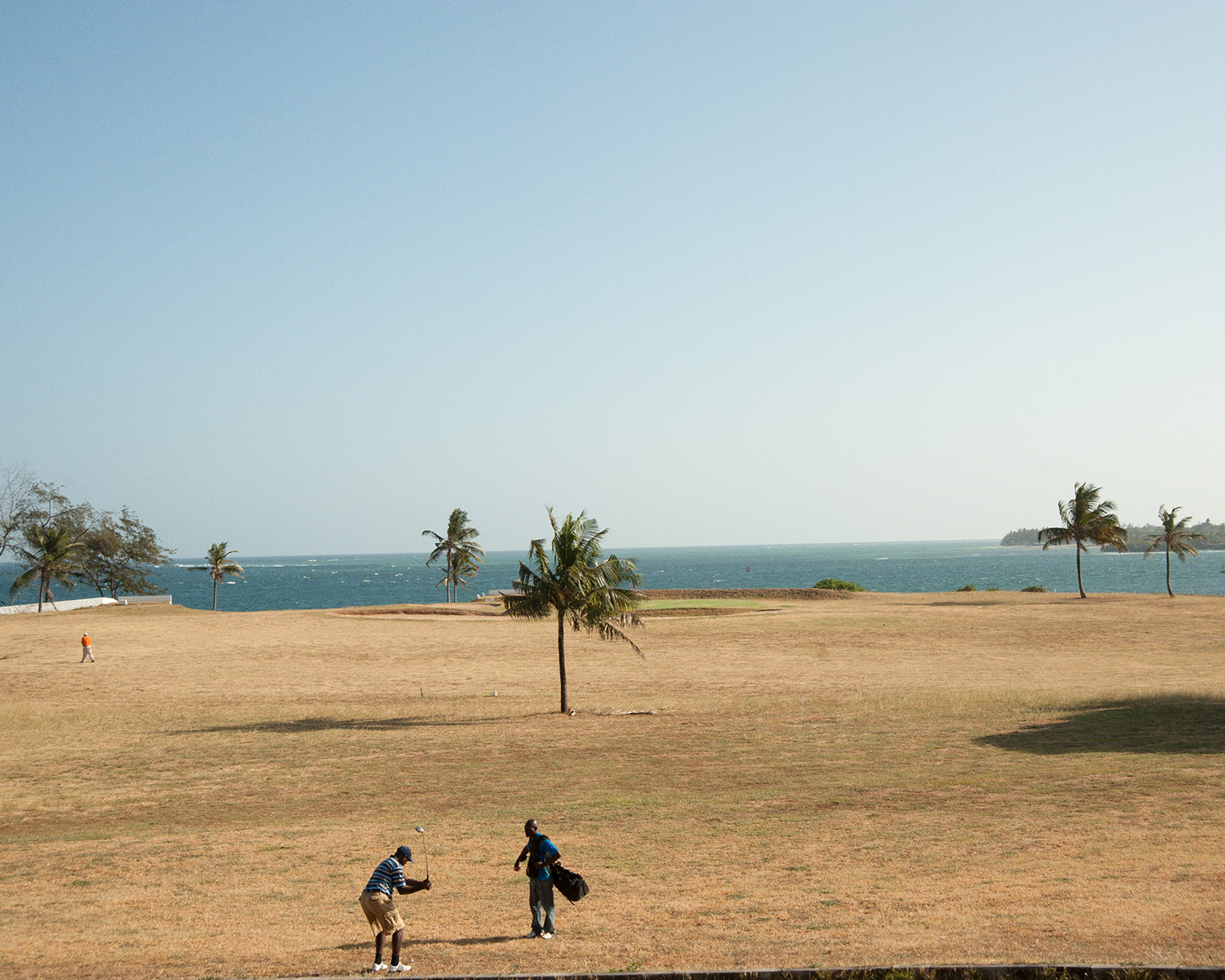 A golfer watched by his caddy is ready to swing at the Mombasa Golf Club.