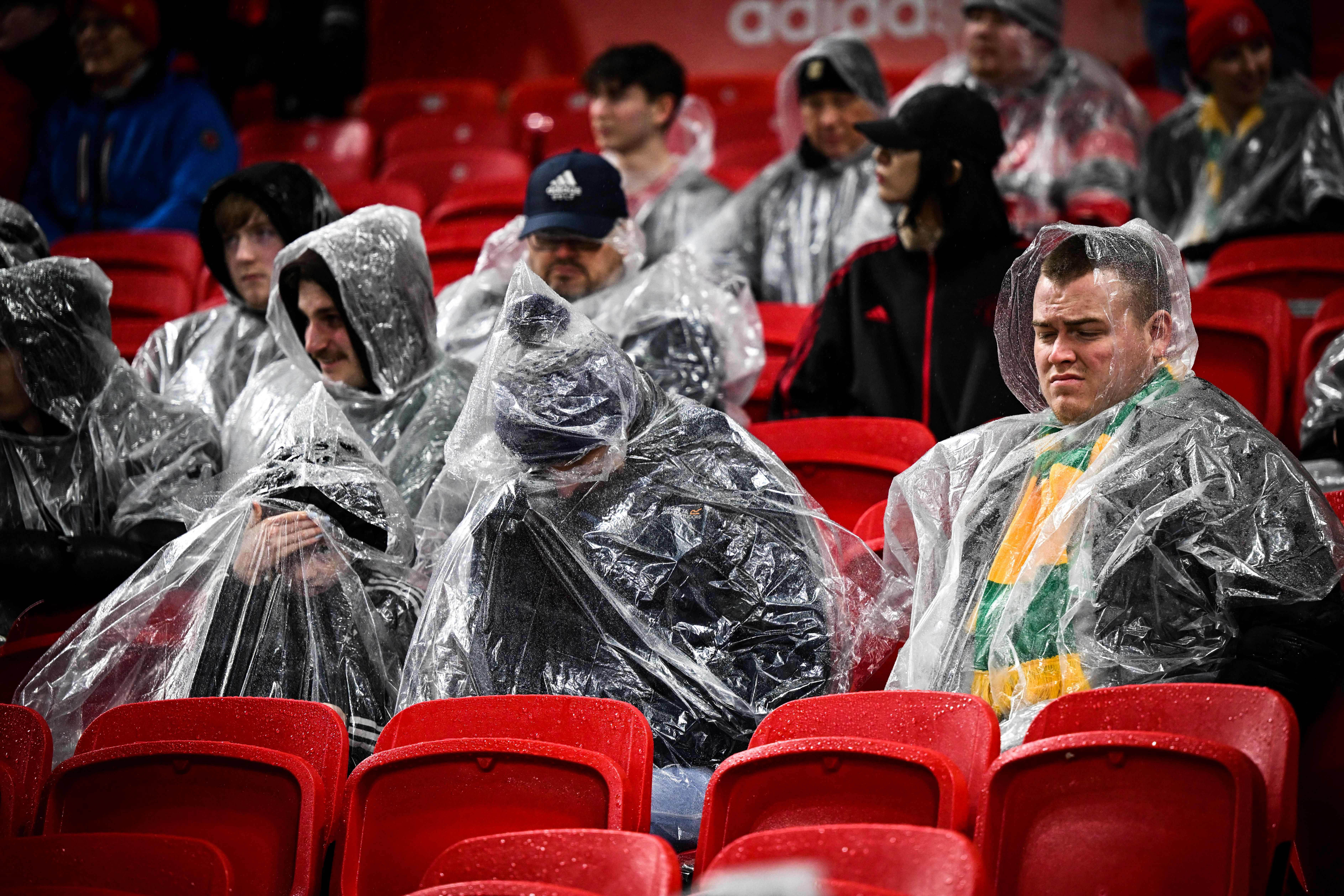 Damp spirits: A fan wearing the colours of Newton Heath, which has become a symbol of protest against the Glazers, gets soaked