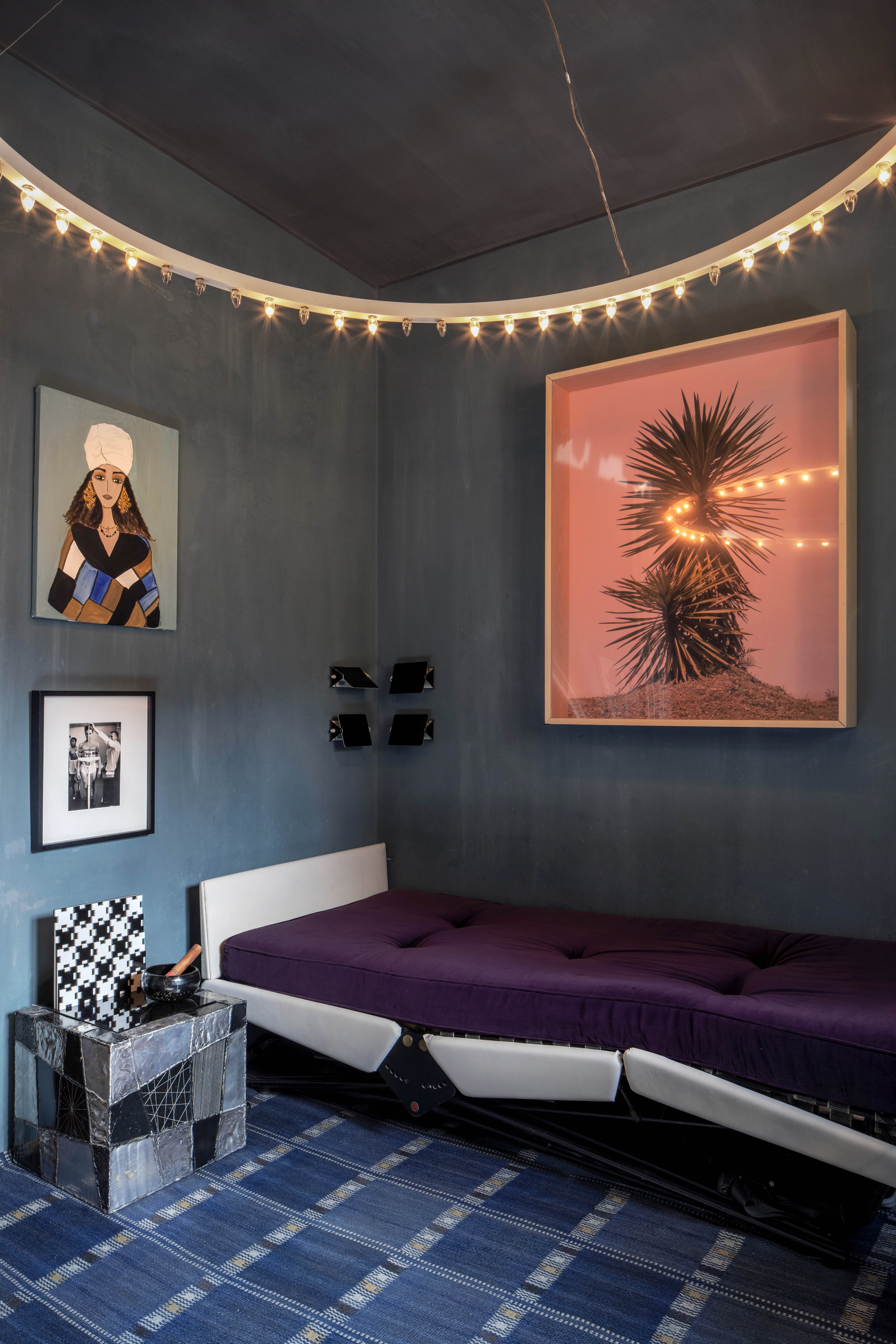 ‘My taste in furniture is not very functional’: a ring of lightbulbs illuminates a spare bedroom, with geometric square bedside table and another fine carpet