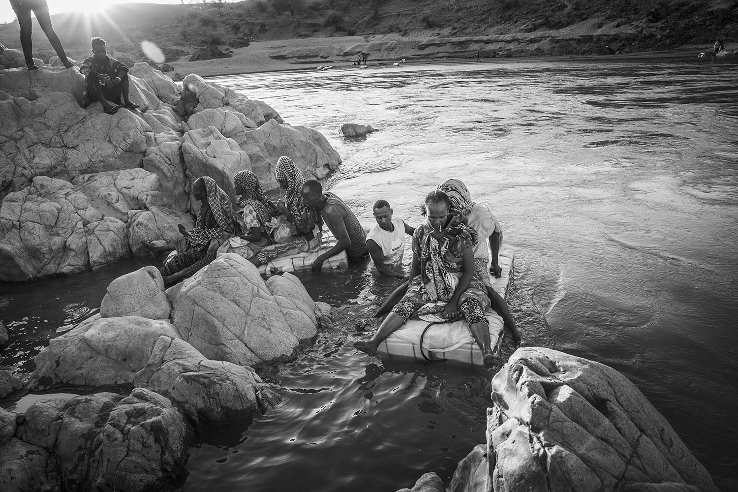Ethiopian women illegally cross the Tekezé River on rafts made from plastic containers in order to reach Sudan