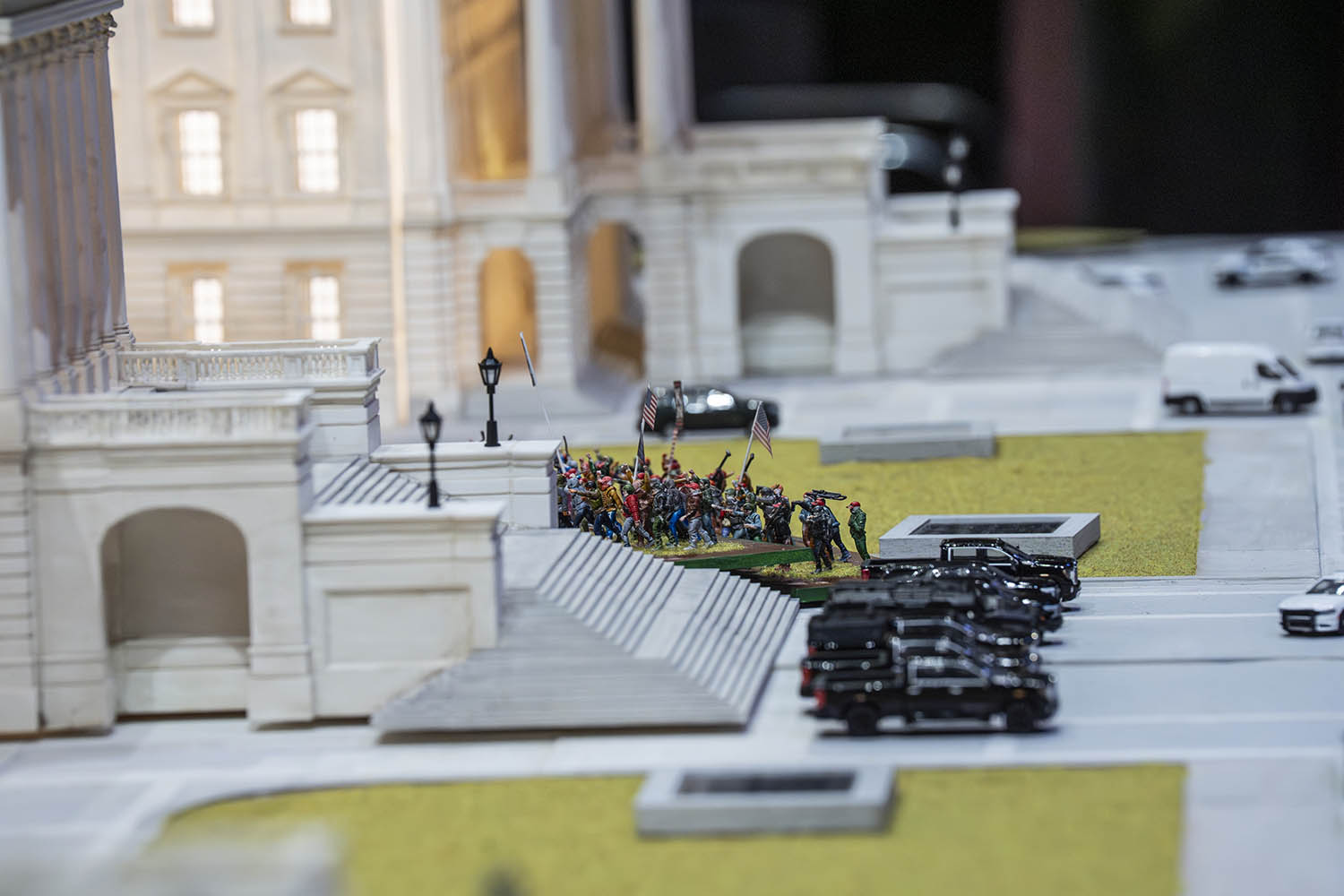 Tiny figures of the Proud Boys line up beside a model Capitol