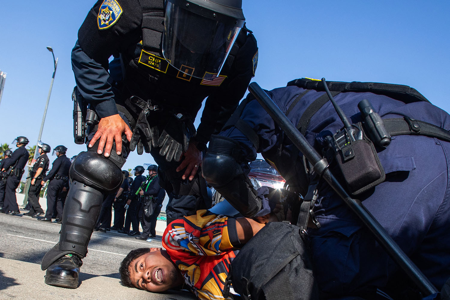 California Highway Patrol officers arrest a demonstrator in the overpass of the 101 motorway on 10 June