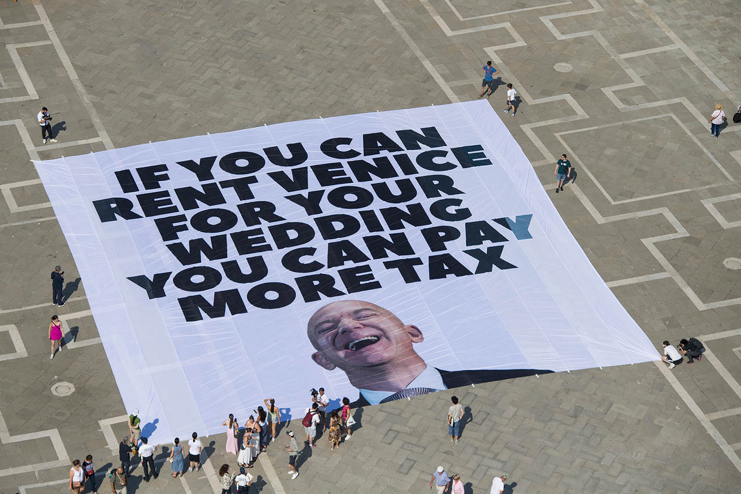 This photo released by Greenpeace shows a large banner against Amazon founder in St Mark’s Square.
