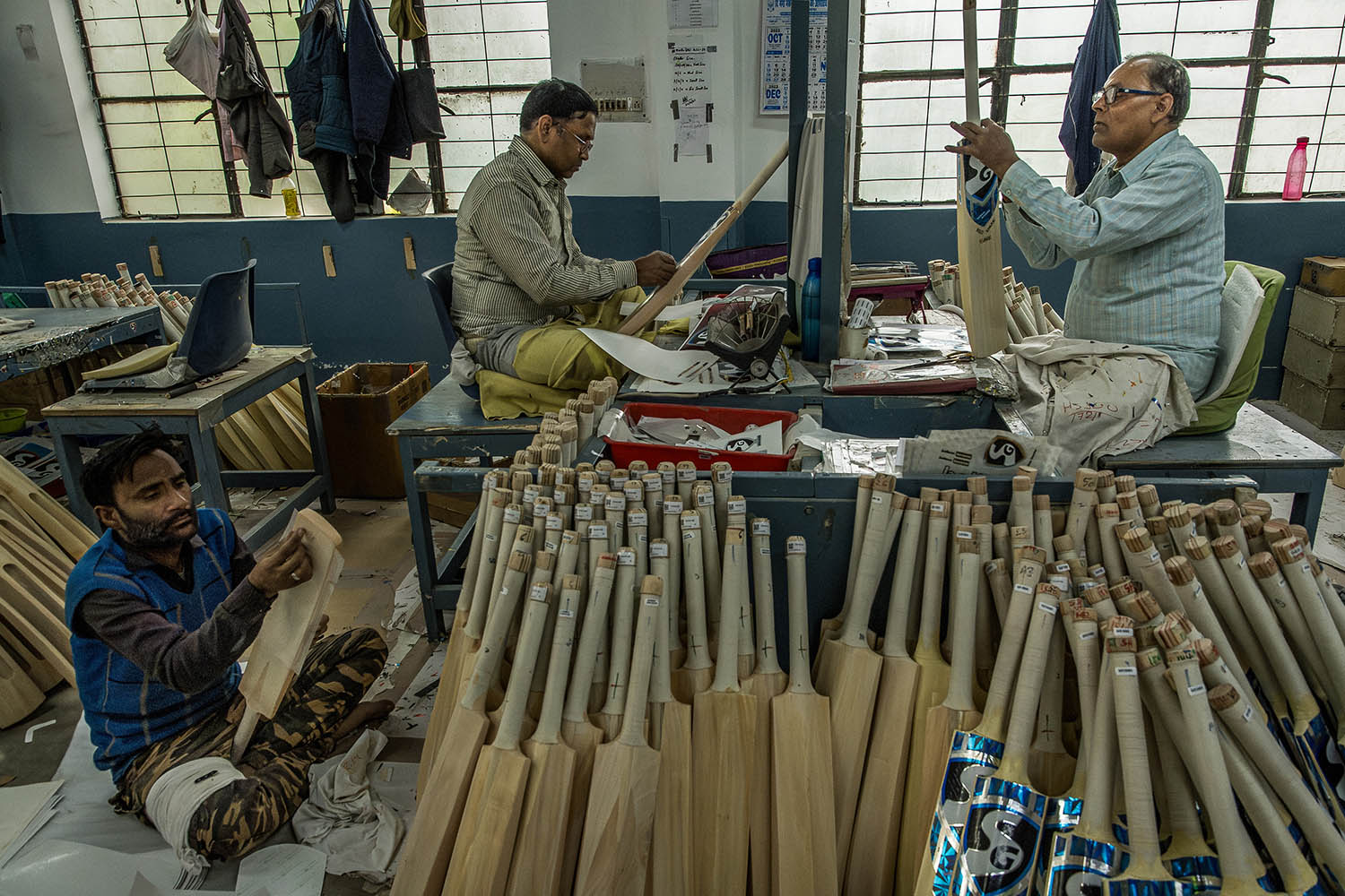Workers in the factory of Sanspareils Greenlands, one of India’s largest cricket equipment manufacturers, fix the brand’s SG stickers to finished bats