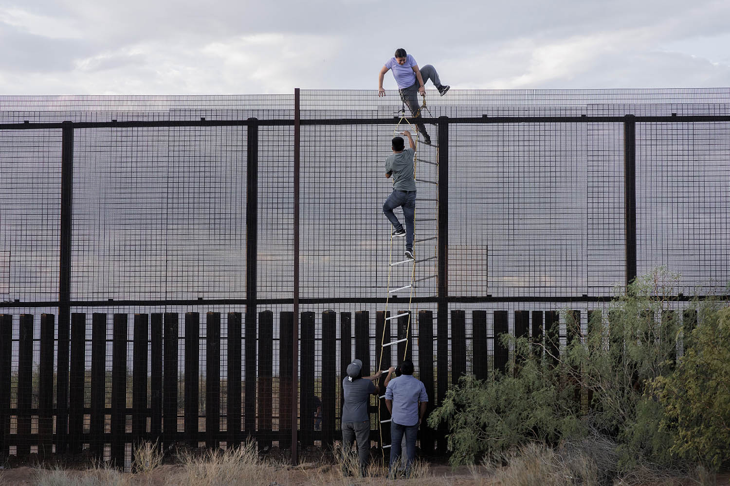 Cartel members use a rope ladeer to orchestrate an illegal border crossing for migrants near El Paso, Texas