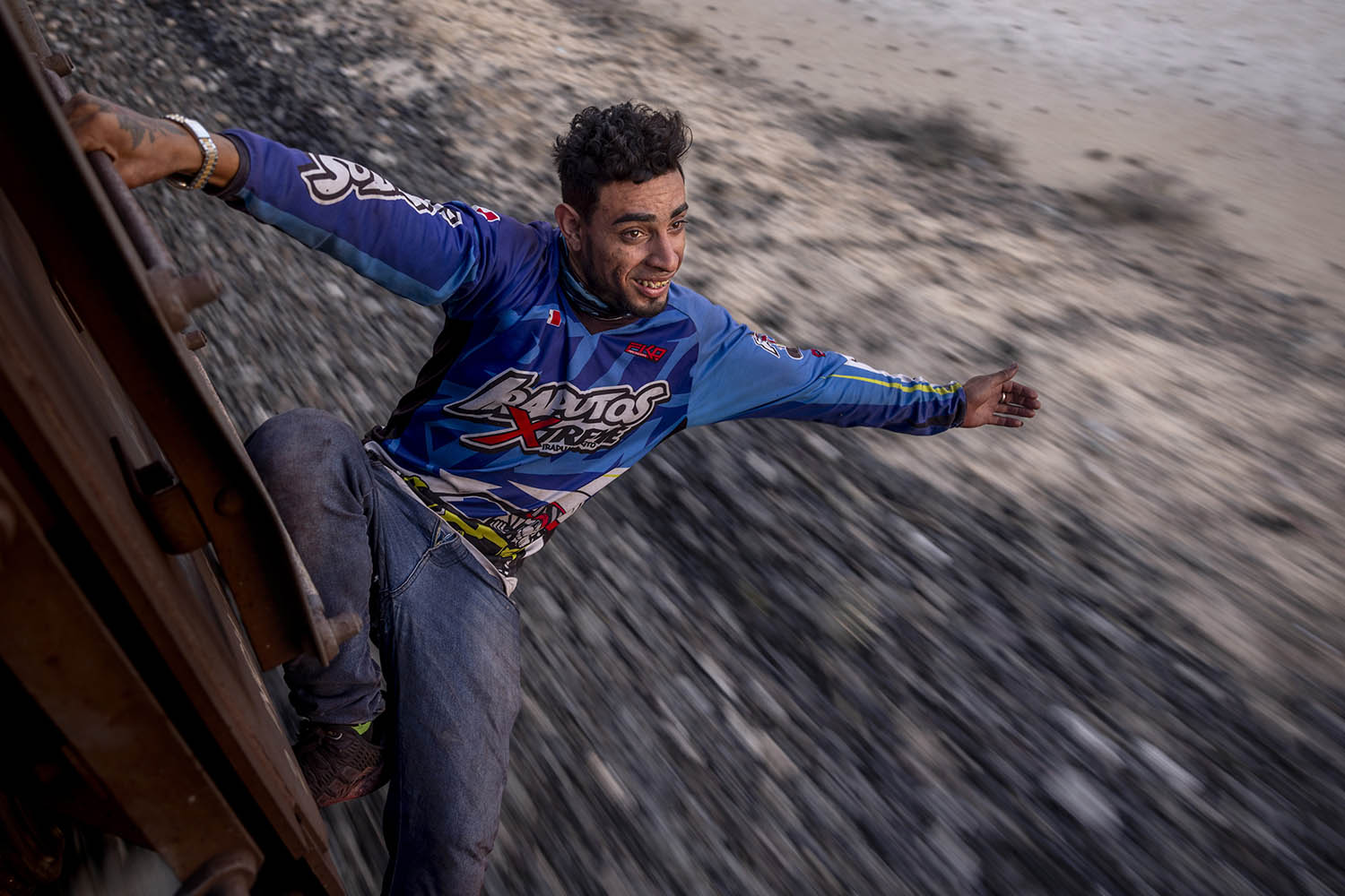 Jean Carlos Vera, 28, from Venezuela, hangs from a wagon. To him, the US means opportunity and freedom from the dictatorship in his homeland
