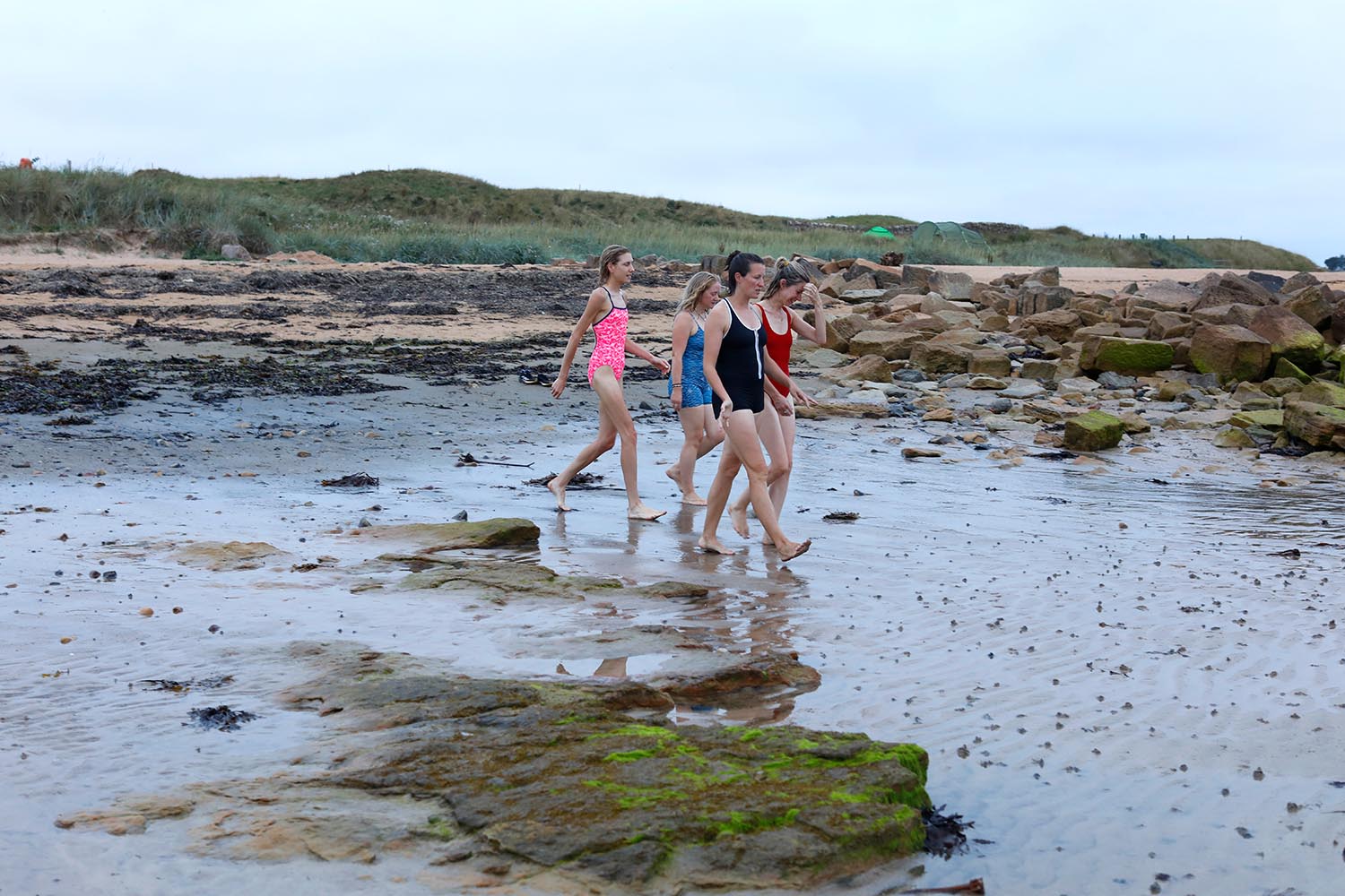 Women at Kingsbarns beach in Fife saunter towards the sea at sunrise