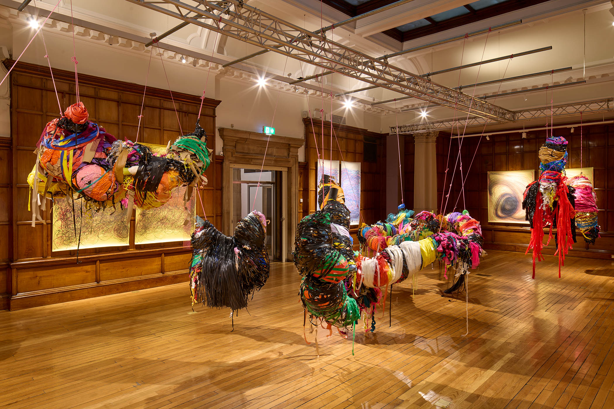 ‘Colourful net, tape and ribbon cocoons bulge like piñatas’: Nnena Kalu’s ‘joyful’ sculptures hang in front of her swirling works on paper.