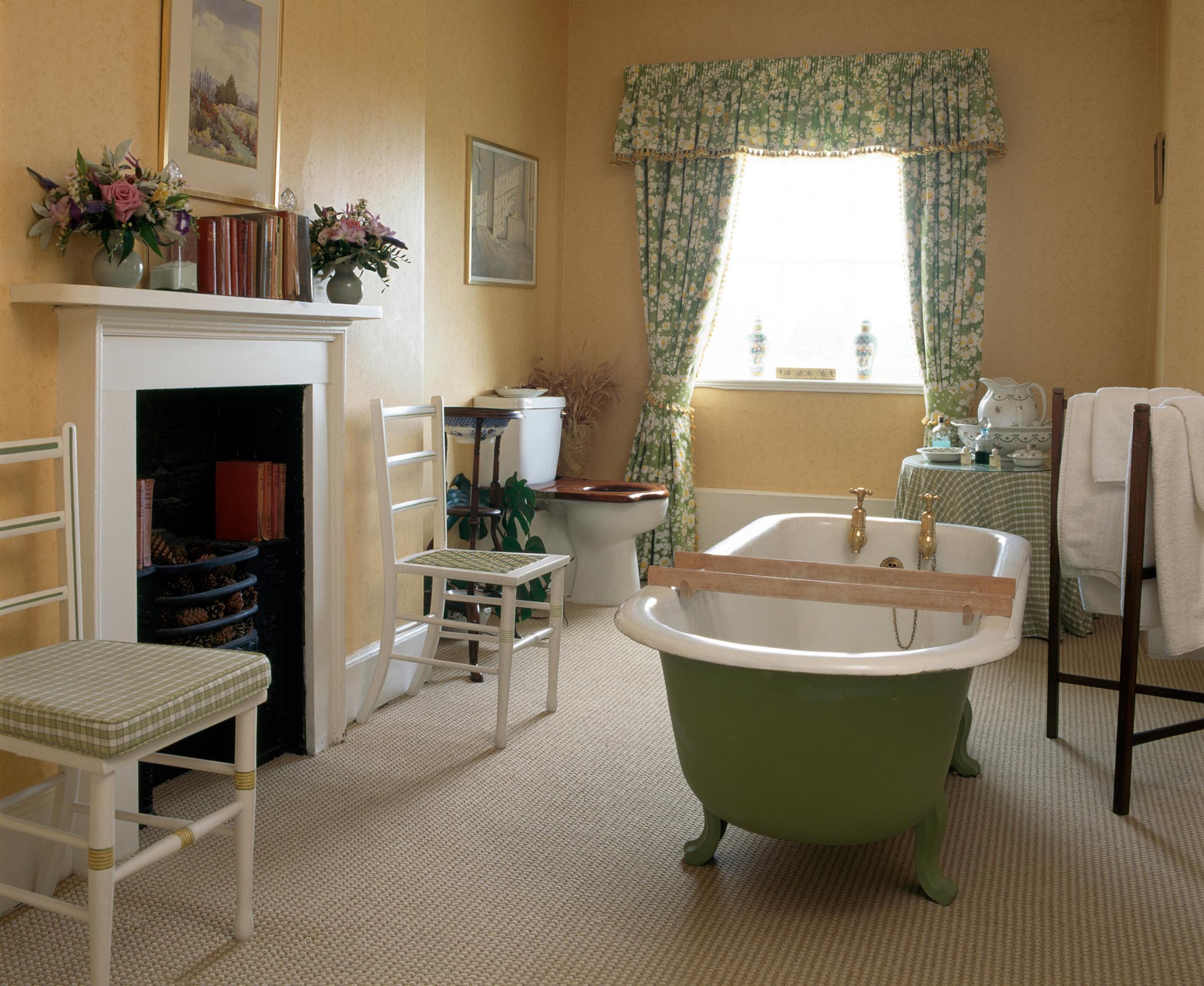 Pale green roll top bath in country bathroom with green floral curtains and a cream carpet