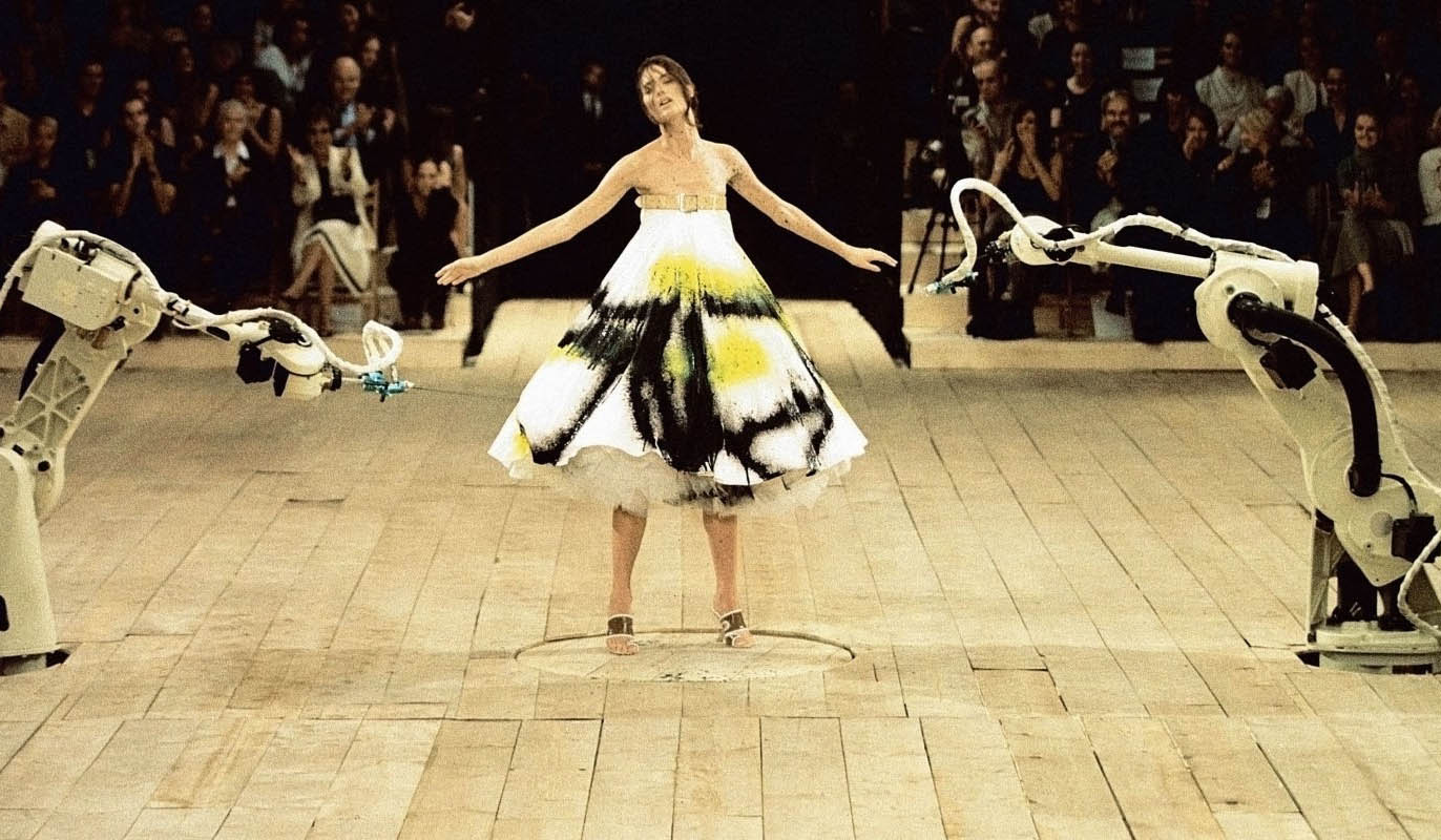 Alexander McQueen SS99 McQueen’s No 13 show, housed in a London warehouse, brought the audience to tears. The late designer was well known for his emotionally charged shows, but Shalom Harlow and the Robots was one of his most dramatic. The show opened with Paralympian and double amputee Aimee Mullins wearing a pair of wooden prosthetic legs created for the event, followed by a cast of 90s models, including Erin O’Connor, Audrey Marnay and Angela Lindvall. As Canadian supermodel Shalom Harlow made her final exit, she stopped between two robot machines. Harlow, a former ballet dancer, began to rotate on wooden turntable as the two robots began to track her movements. The tempo of the music changed and the spray paint attack began. As Harlow swirled, her dress transformed into a living work of art. Jo Jones
