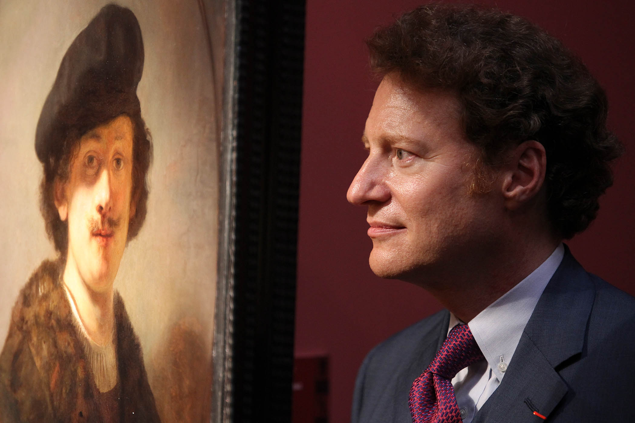 American collector Thomas Kaplan poses for a photo with his painting, Self-portrait with Shaded Eyes (1634), by Rembrandt van Rijn.