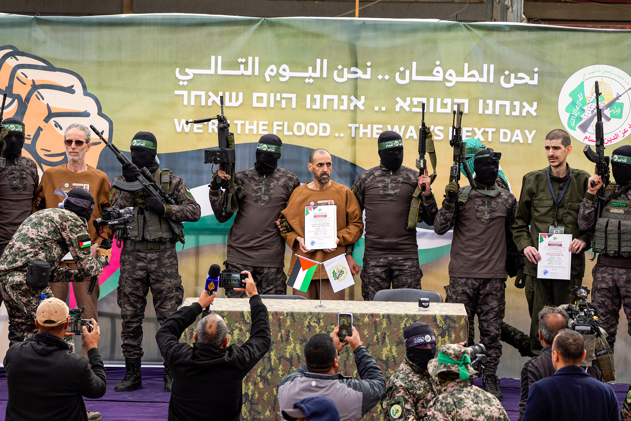8/2/25: Israeli captives, from left to the right, Ohad Ben Ami, Eli Sharabi and Or Levy are escorted by Hamas fighters on a stage before being handed over to the Red Cross
