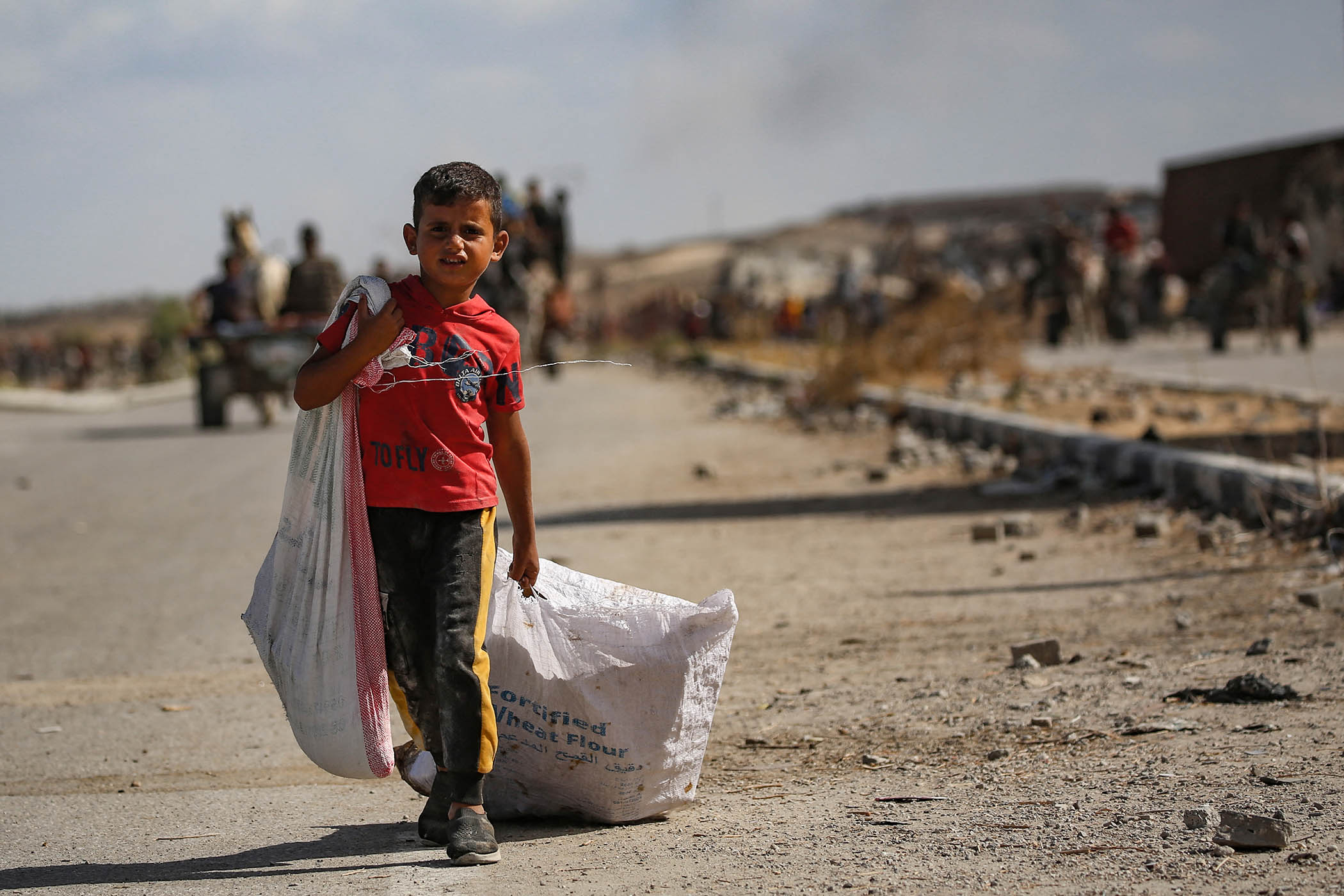 A Palestinian boy carries a bag of food from a distribution point run by the Gaza Humanitarian Foundation