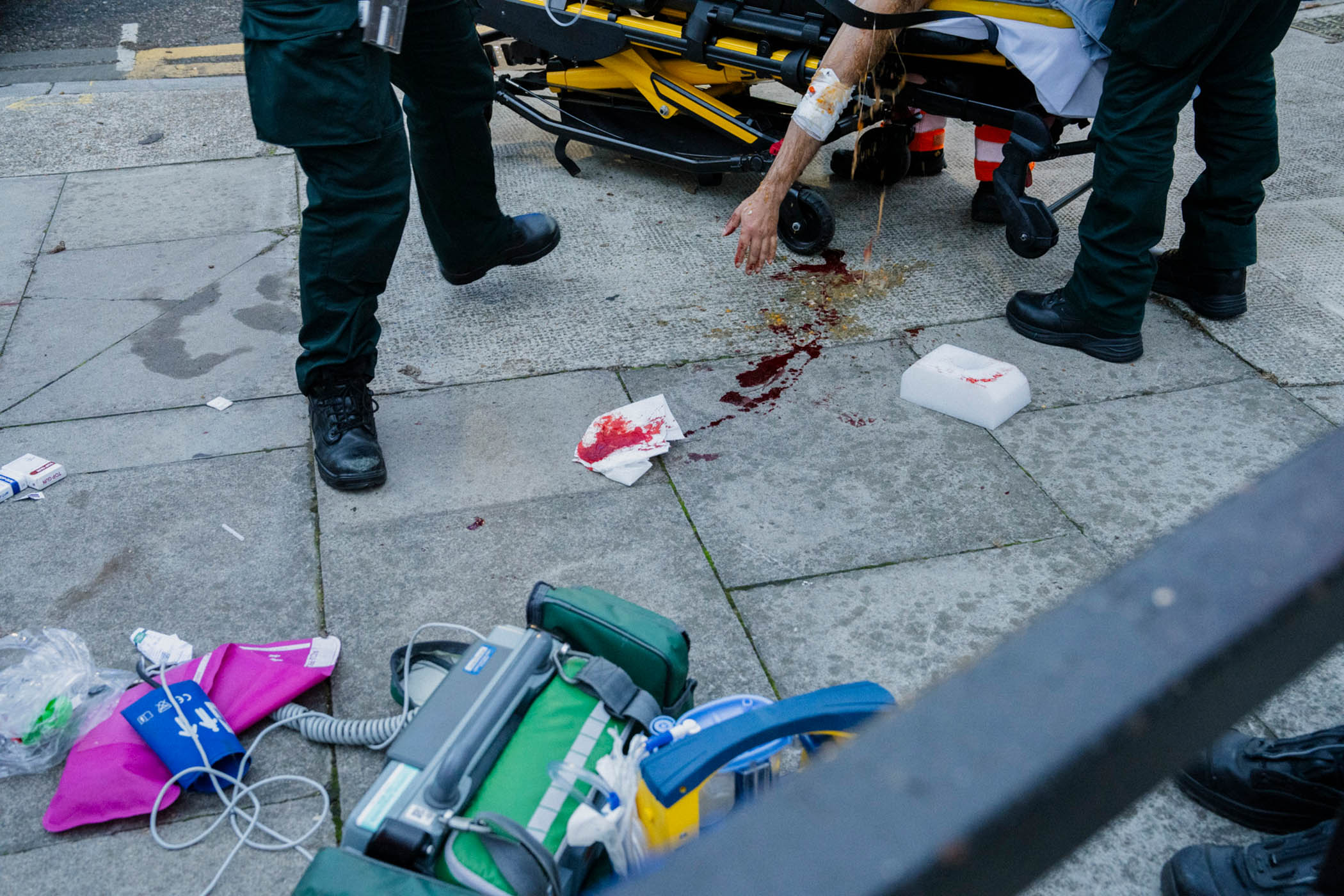 The blood and vomit of a middle-aged man with a head injury runs across the pavement