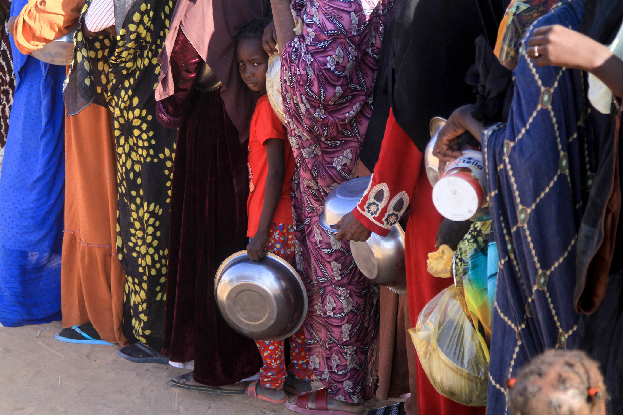 Displaced women queue for food at a camp in Al-Dabbah, northern Sudan