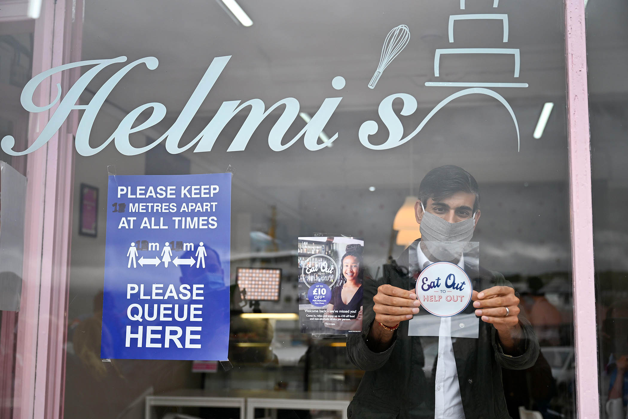 Rishi Sunak places an Eat Out to Help Out sticker during a visit to Rothesay on the Isle of Bute, Scotland