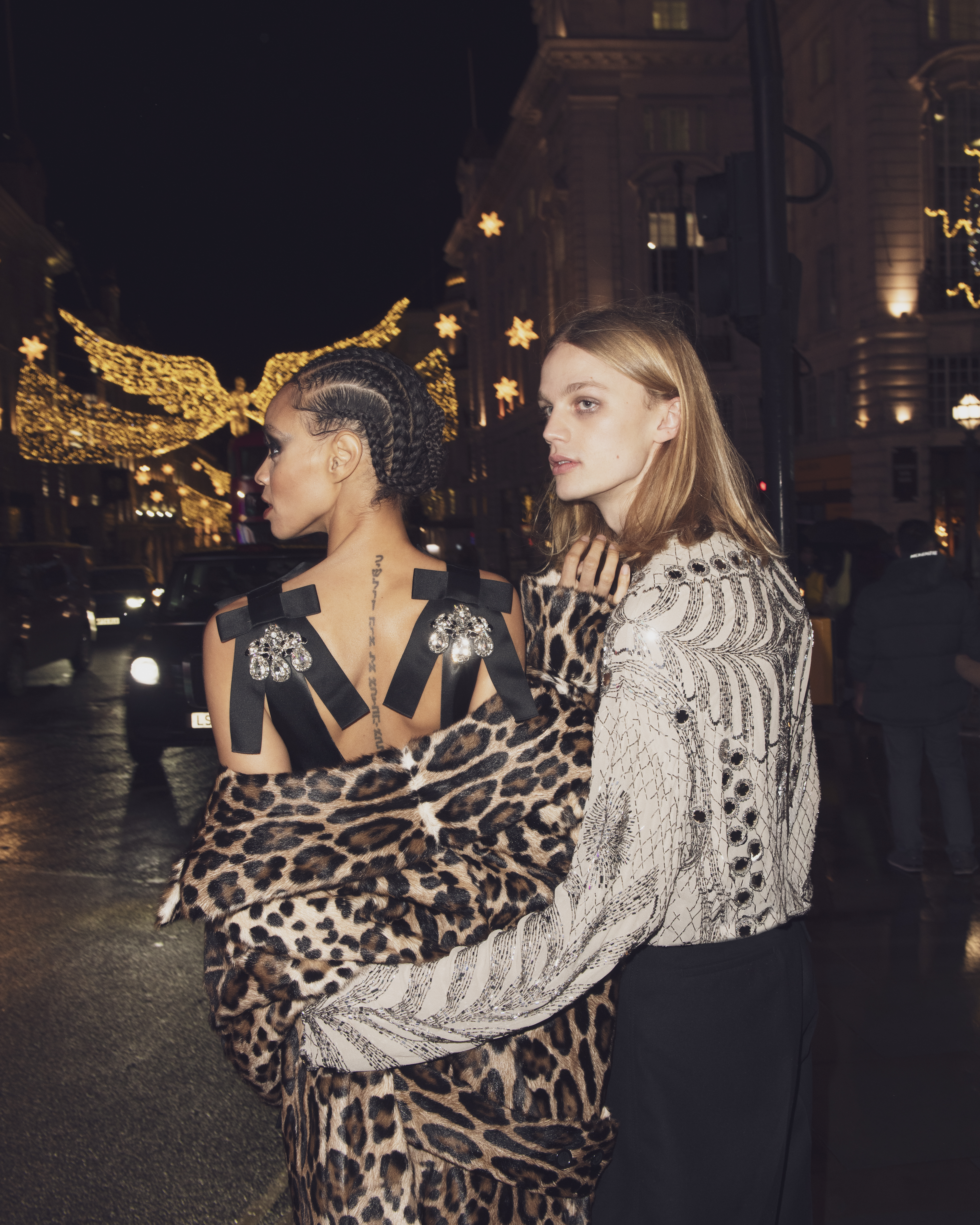 Akira wears leopard print coat and rhinestone dress by Dolce & Gabbana. Olo wears embroidered long sleeve top, and pleated trousers by Lanvin