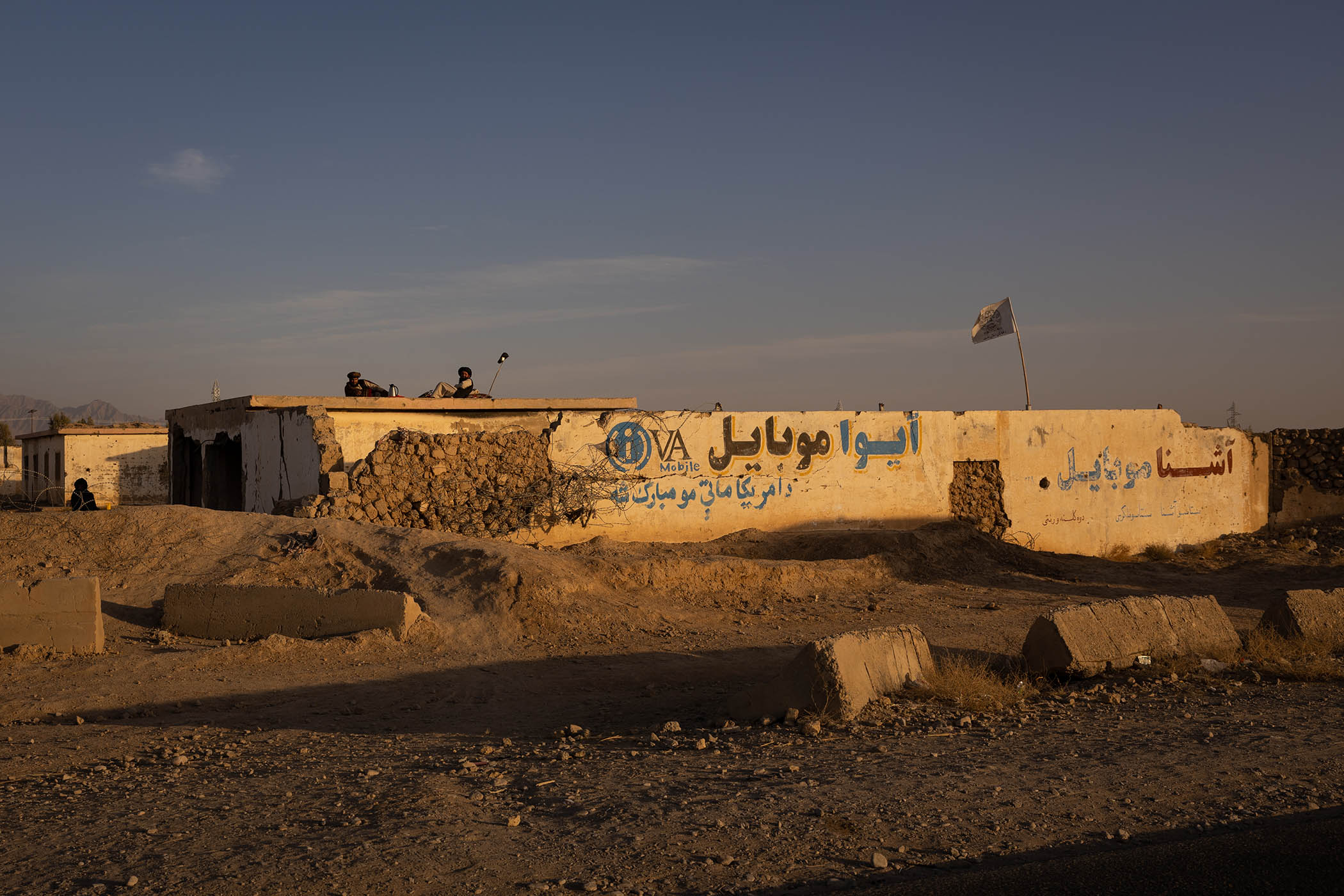 Members of the Taliban lie on the roof of a partially destroyed former military base on the road into Sangin