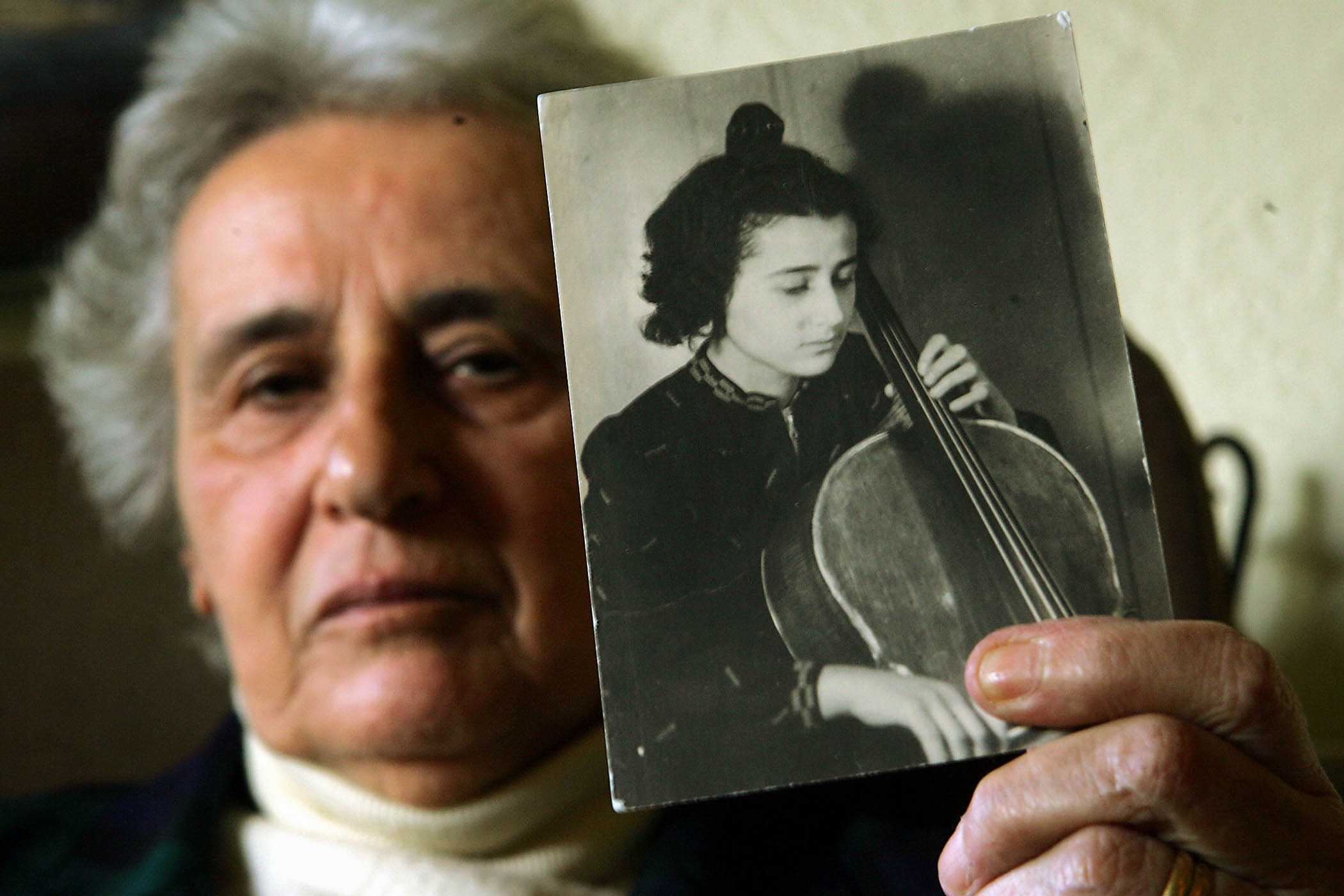 Holocaust survivor Anita Lasker-Wallfisch holds up a portrait of herself playing the cello taken in Berlin before she was transported to Auschwitz