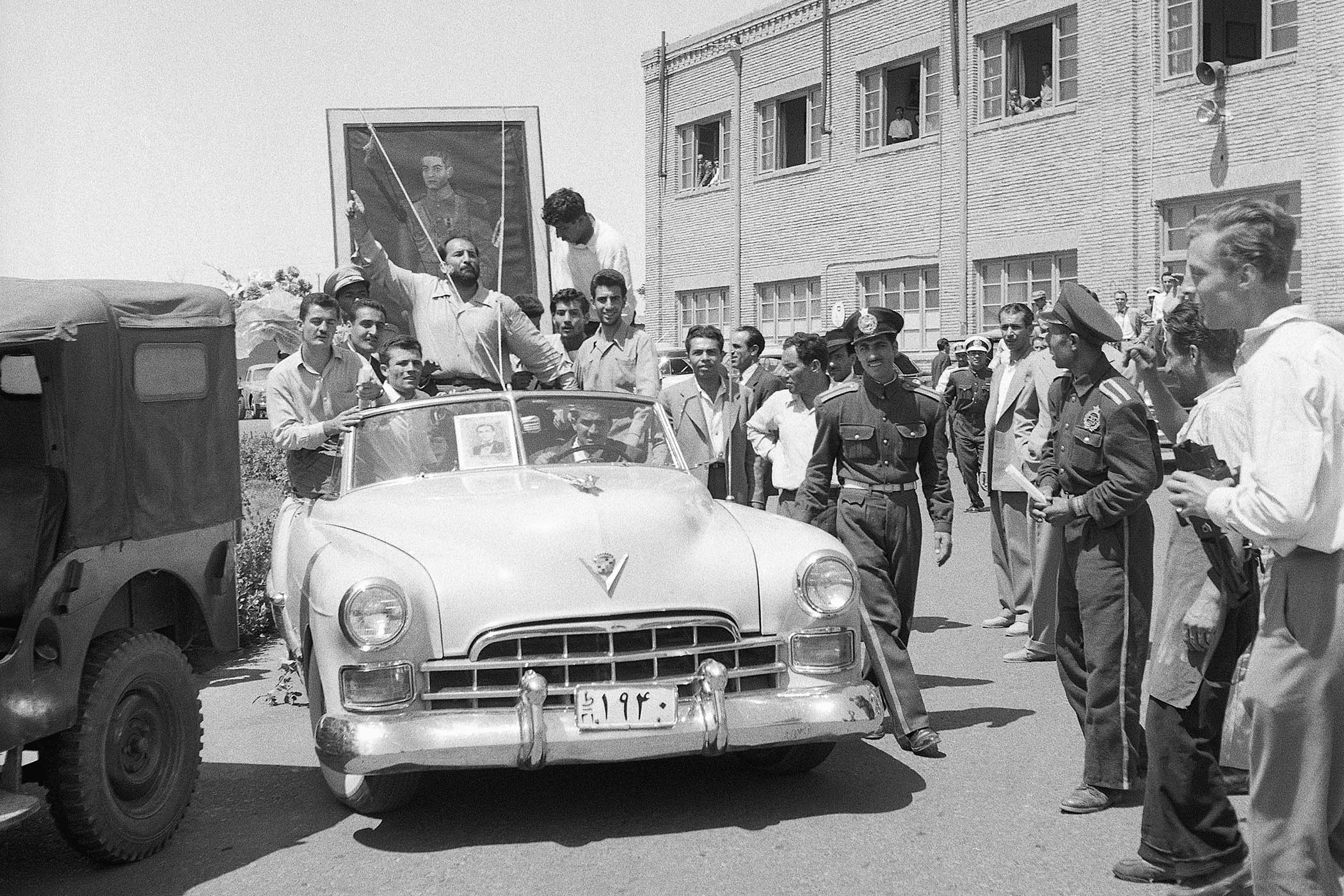 A portrait of the Shah of Iran is carried through the streets of Tehran by followers of the monarch, as he makes his return to the capital after a brief exile, 1953