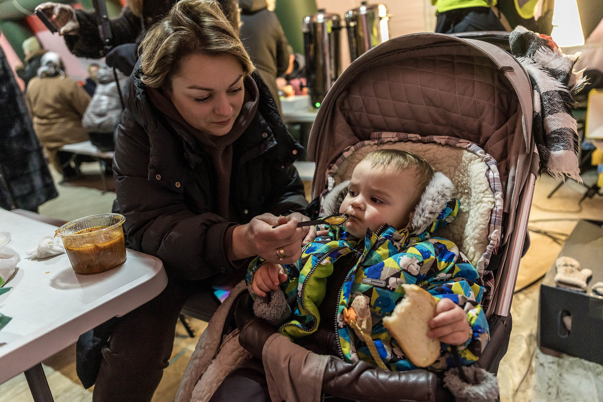 Yulia Dolodova feeds her son hot soup she received from the World Central Kitchen