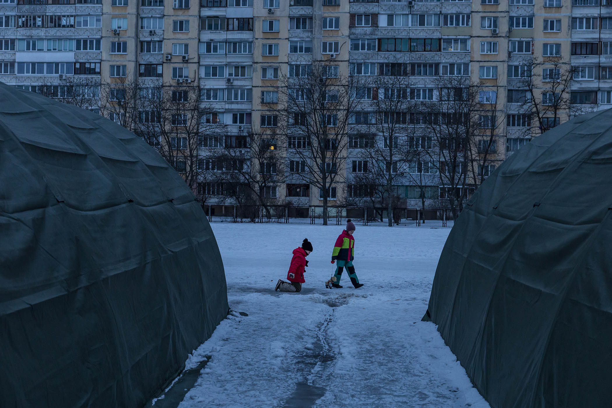 Children walk past tents set up by emergency services that offer electricity and heat