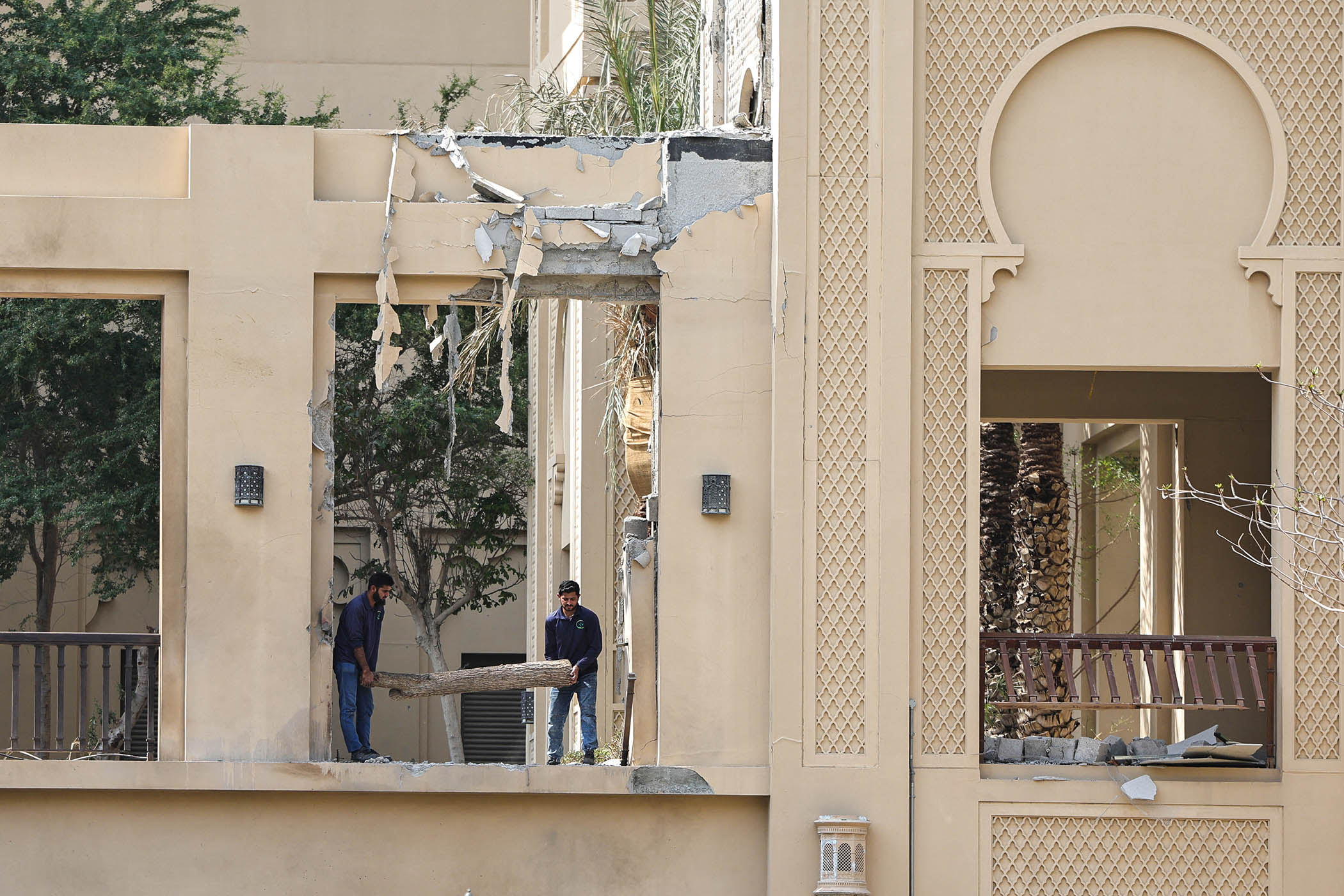 Workers clean debris after an Iranian strike at the Fairmont hotel in Dubai