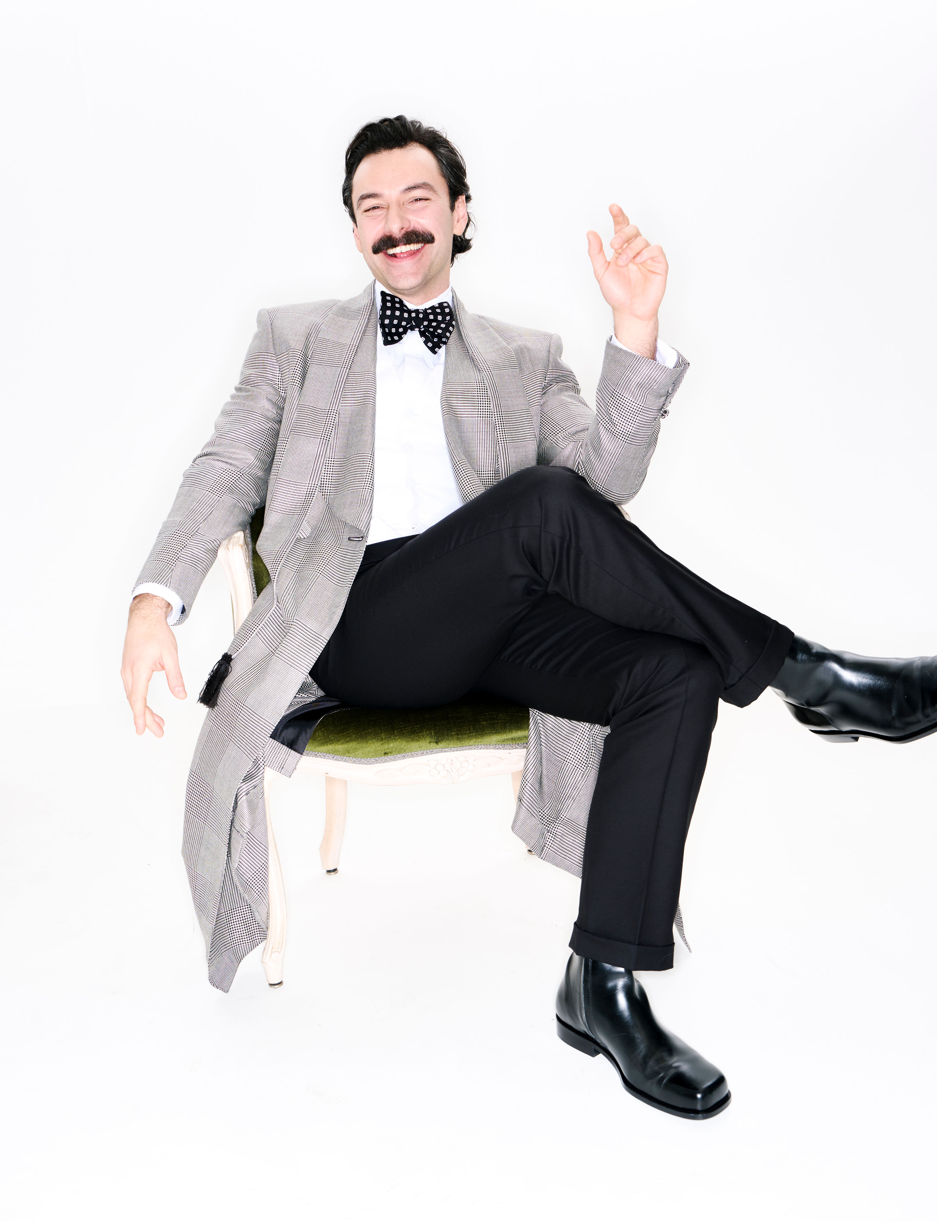 Aidan Turner wears coat, shirt, trousers, and bow tie by Dunhill and shoes by Ami.