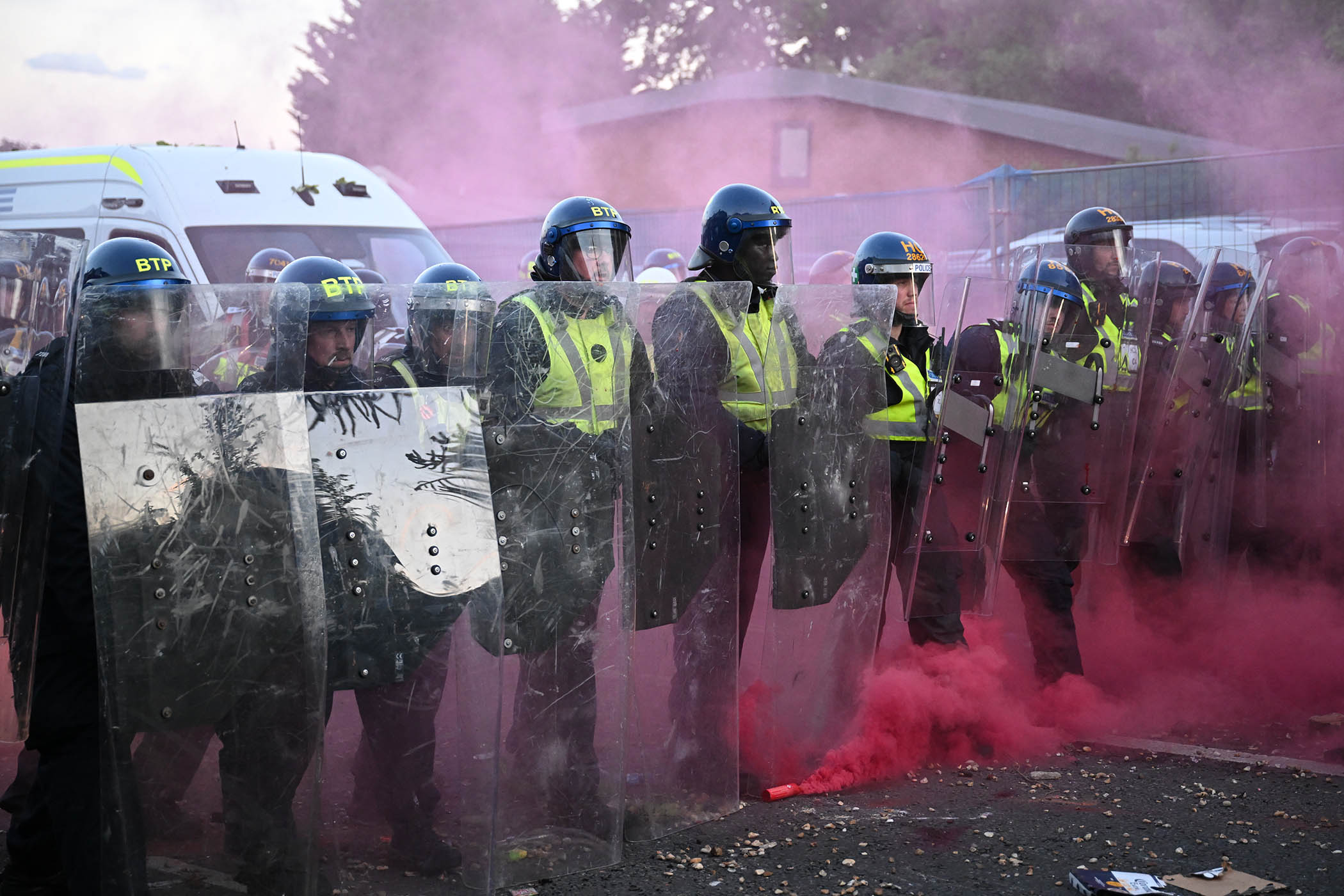 A flare blows smoke as riot police stand near protesters as they gather near the location where Henry Nowak died during a demonstration over the police’s handling of the incident