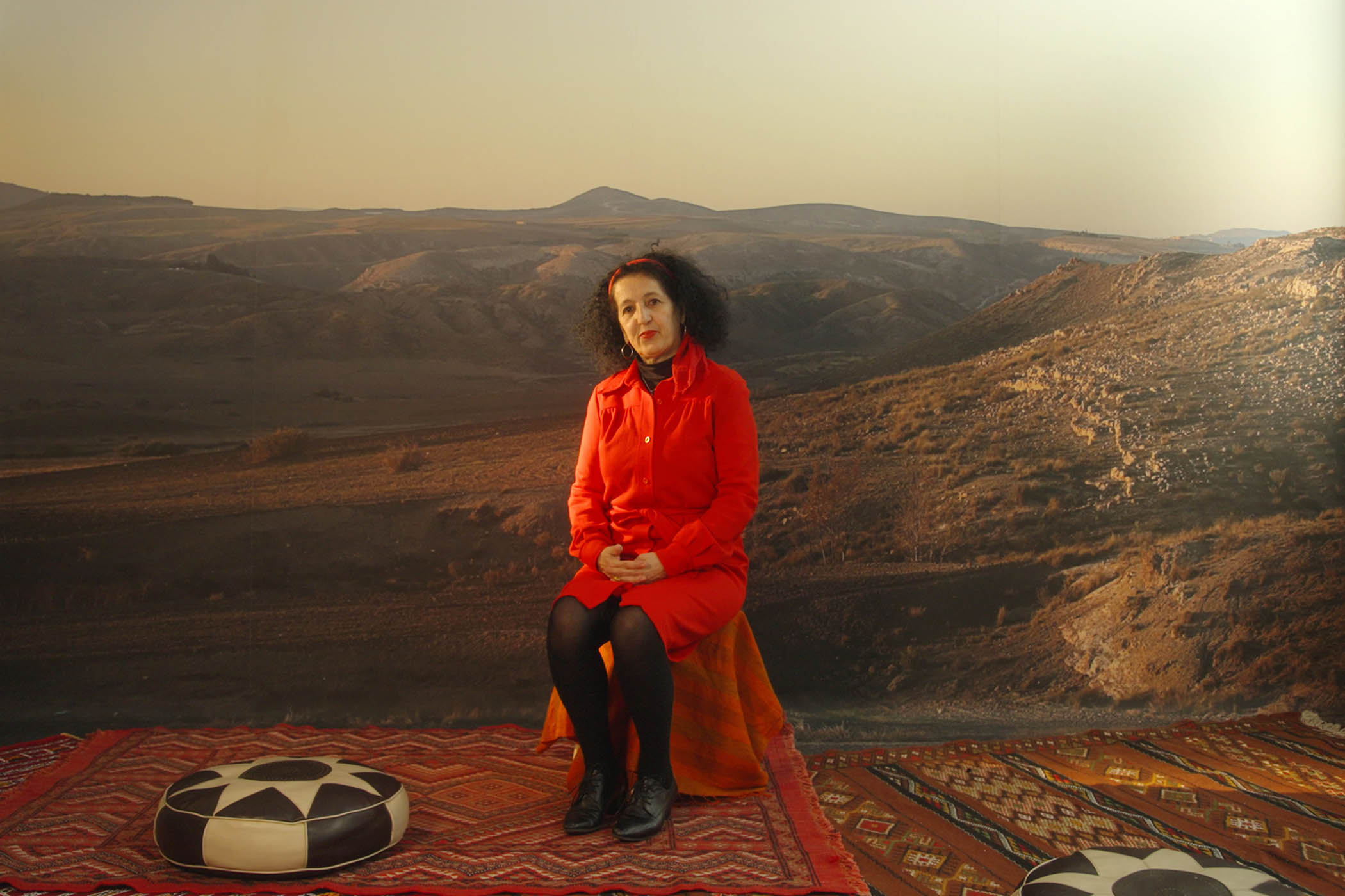 ‘You will see her on and off in her trademark red clothes as you pass through this cinematic tribute to Algerian cinema’: Zineb Sedira