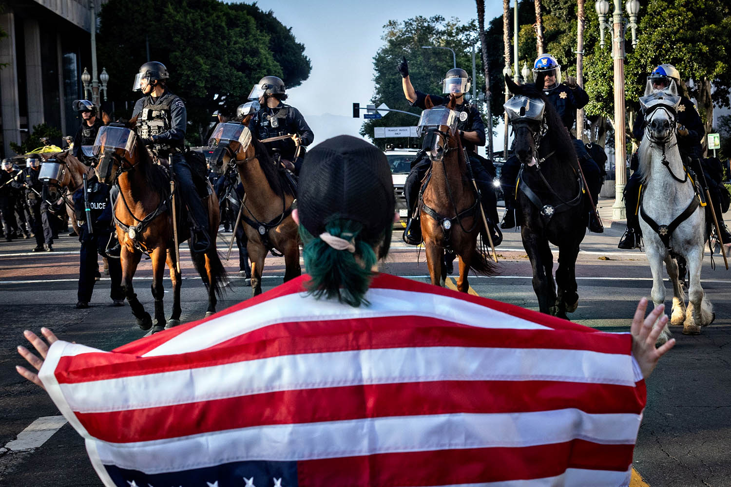 A demonstrator faces mounted police near Los Angeles city hall