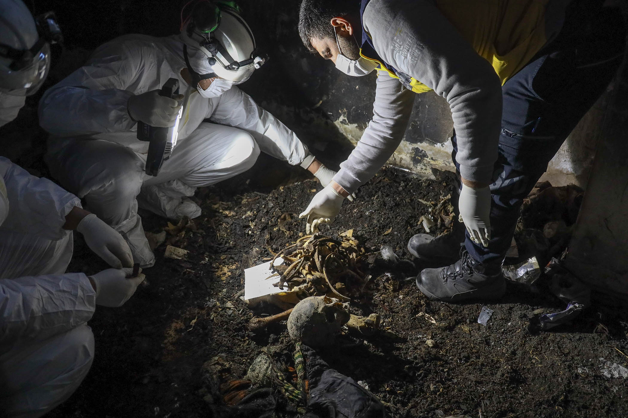Syrian civil defence workers collect human remains found in basements on the outskirts of Damascus in 2025