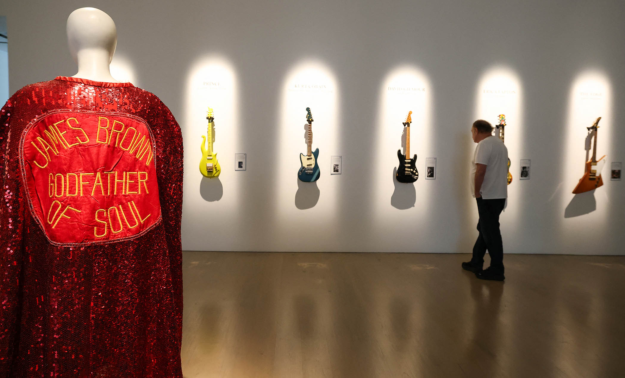 James Brown’s stage-worn sequined cape is displayed as a visitors look at (L-R) Prince’s Andy Beech custom Yellow Cloud guitar, Kurt Cobain’s 1966 Fender Mustang, David Gilmour’s "Black Strat", Eric Clapton’s "The Fool" Gibson SG and The Edge’s Gibson Explorer during a press preview of the Jim Irsay Collection at Christie’s