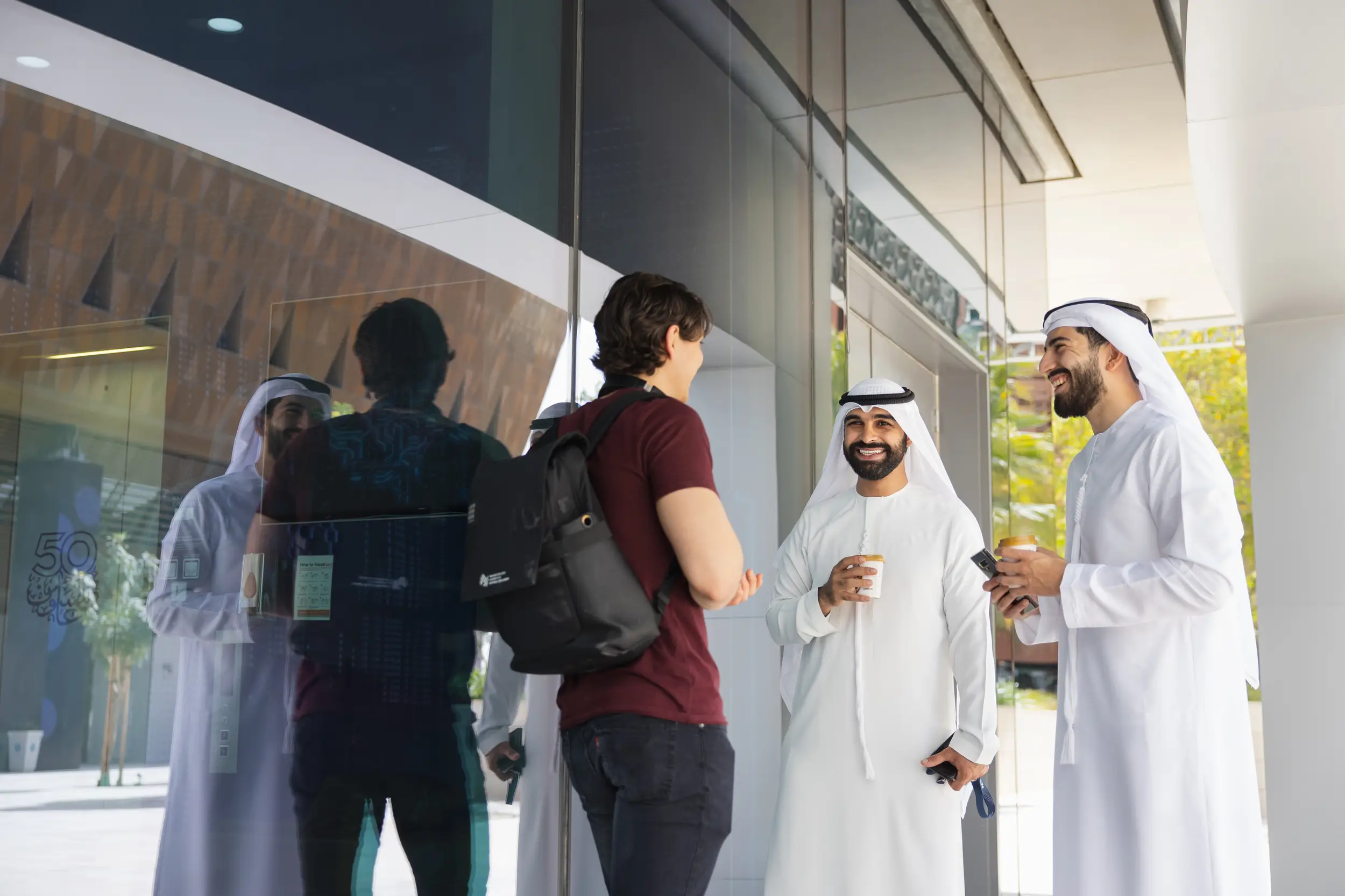 People talking outside a building on the MBZUAI campus