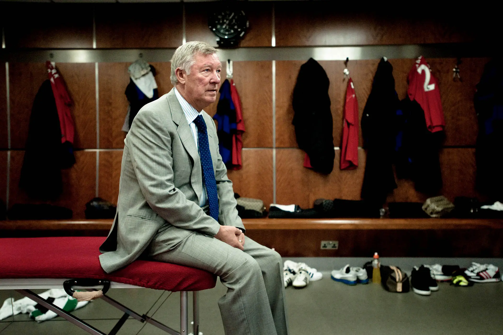 Sir Alex Ferguson sitting on a physio bench in the Old Trafford dressing room